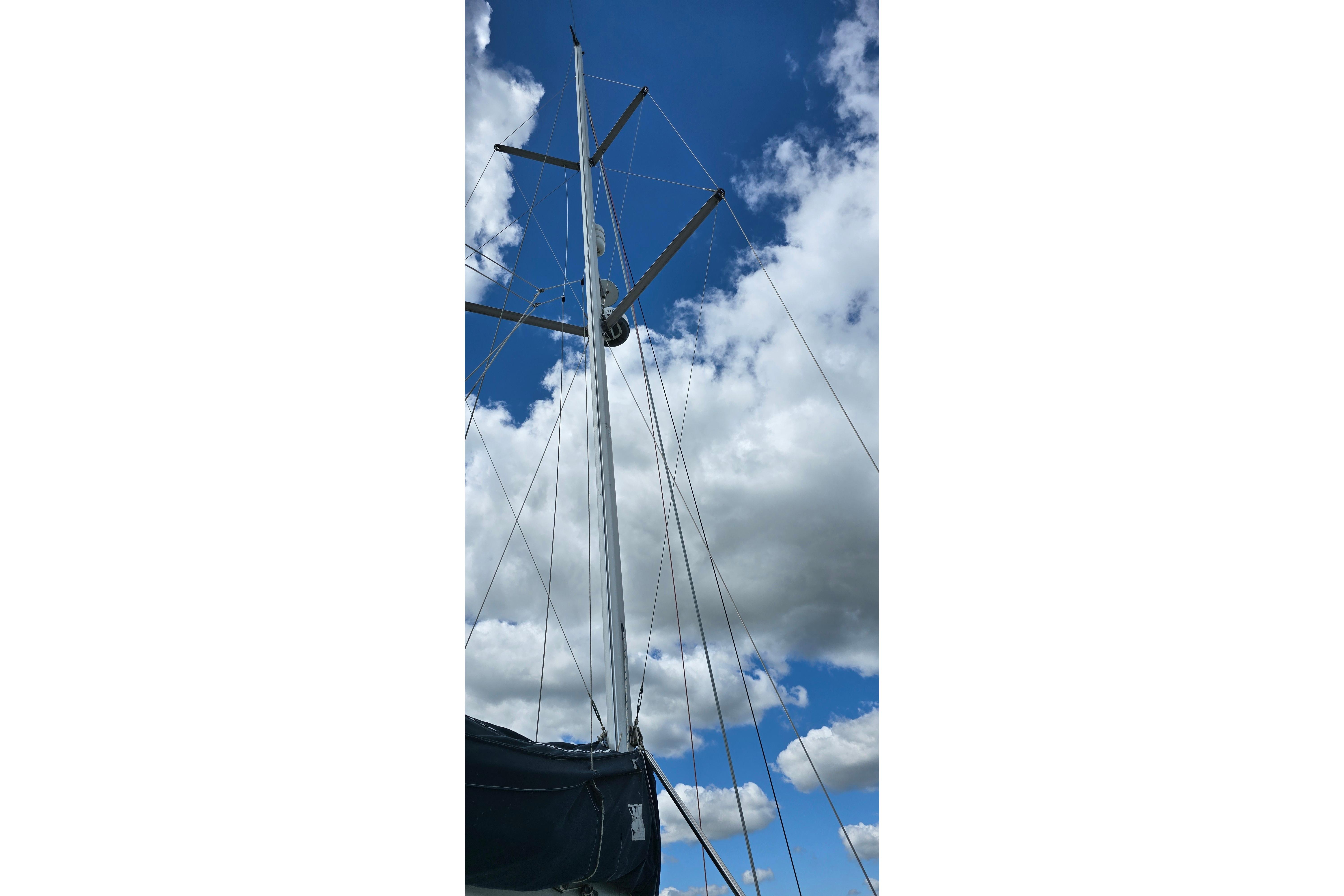 Sailboat mast of 1998 Hunter 410 against a cloudy blue sky.