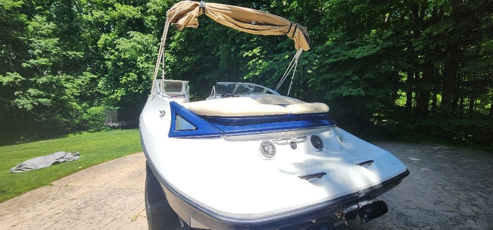 A 2007 Sea-Doo Sport Boat 230 Challenger SE on a paved area, surrounded by trees.