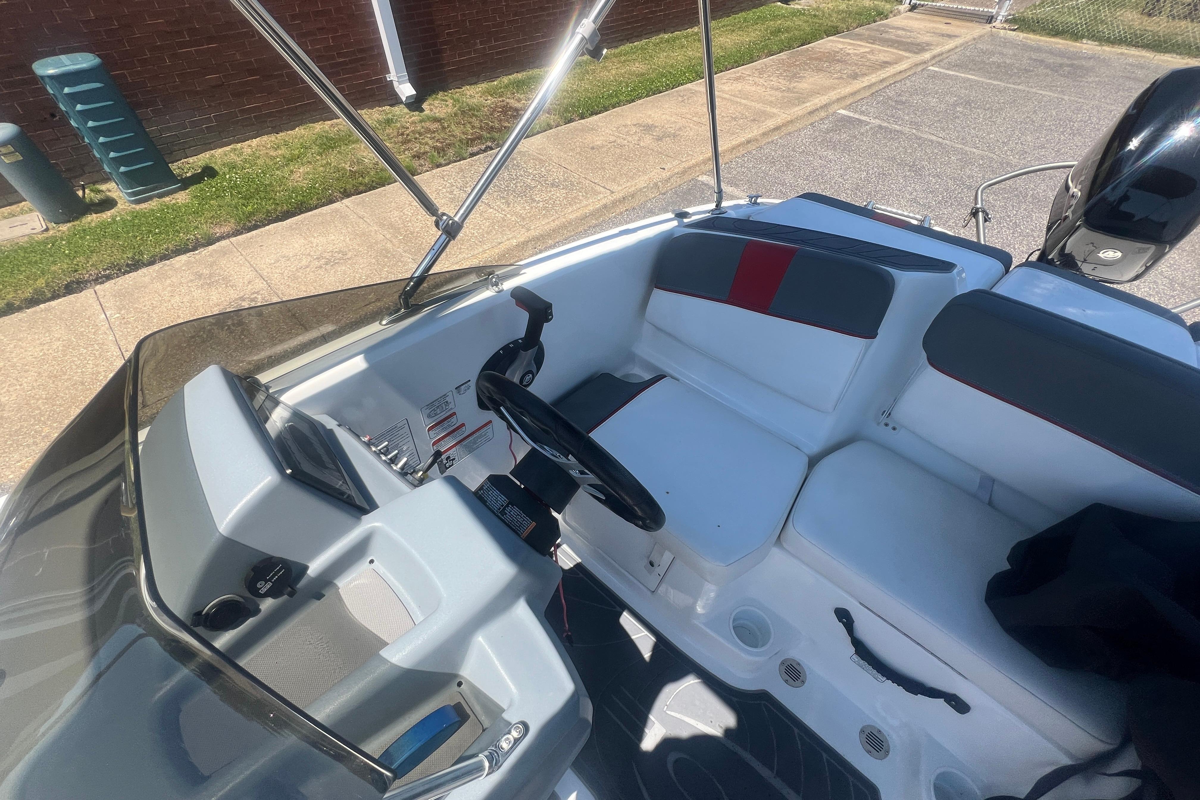 2023 Tahoe T16 boat interior with steering wheel and seating, parked on pavement.