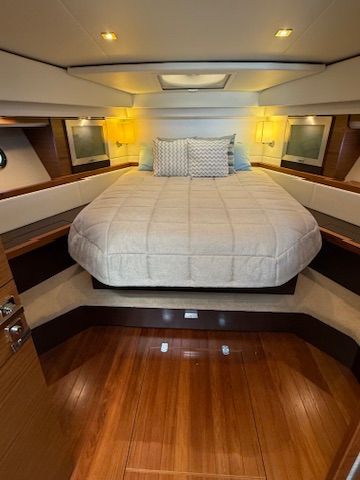 The image shows a luxurious cabin with a large bed and wooden floors.