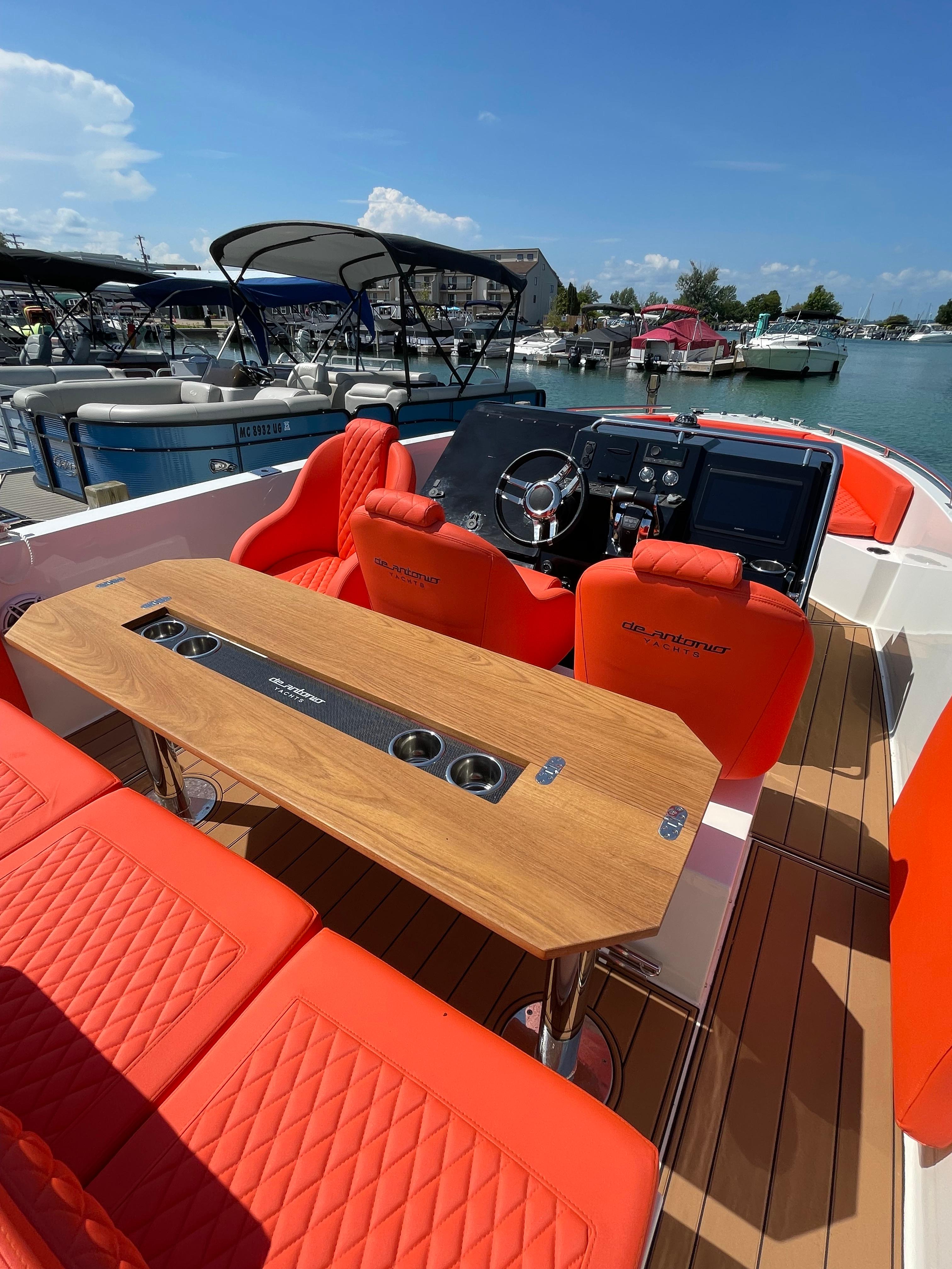 2020 De Antonio Yachts D 28 with orange seating and wooden table docked at marina.