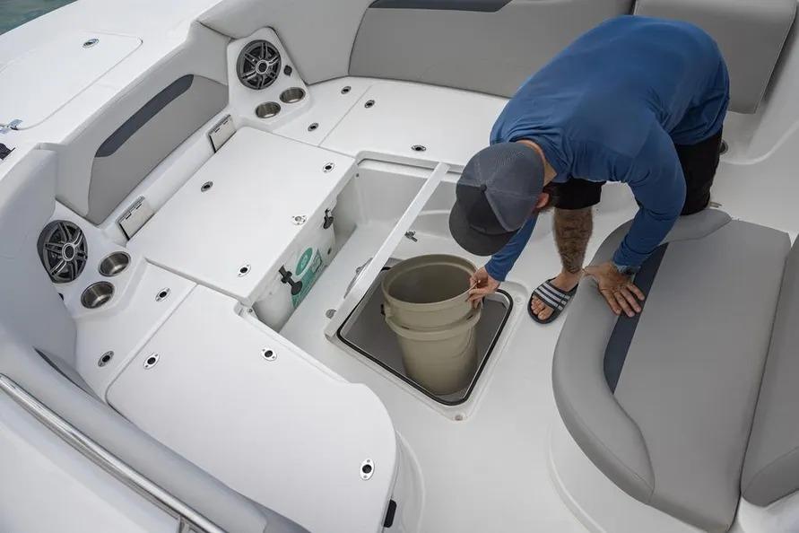 Man inspecting storage compartment on 2025 Hurricane Center Console 24 OB boat.