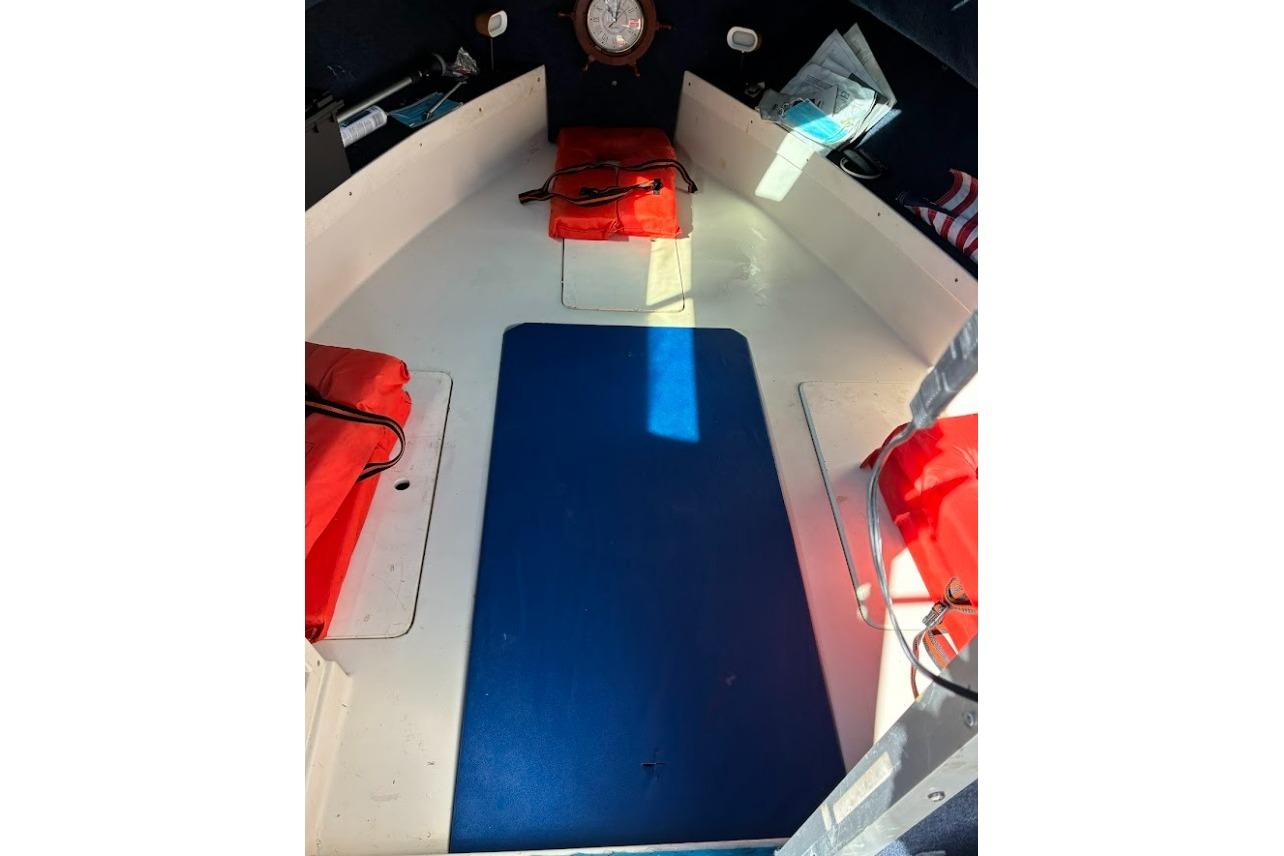 Interior of a 1989 Grady-White Offshore 242 boat with red cushions and blue mat.