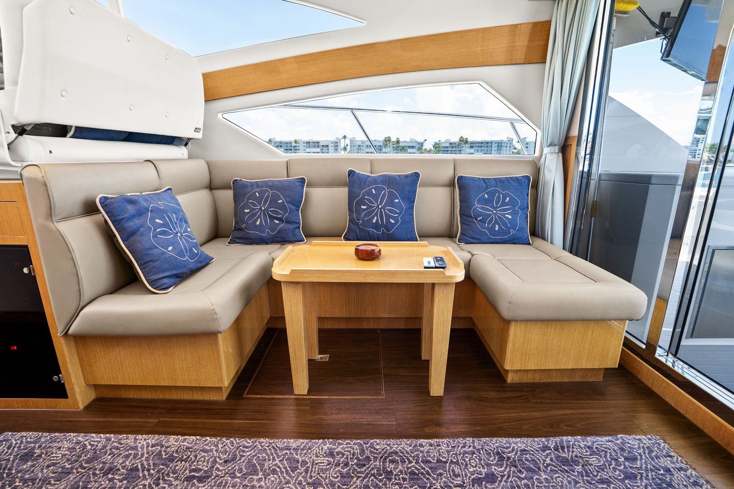 Interior of a modern yacht with beige sofa and wooden table.
