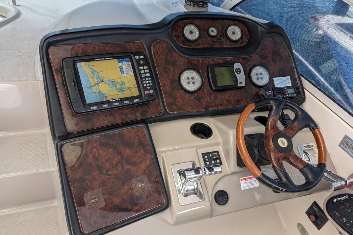 Cockpit of 2003 Cruisers 3970 yacht with navigation system and wooden steering wheel.