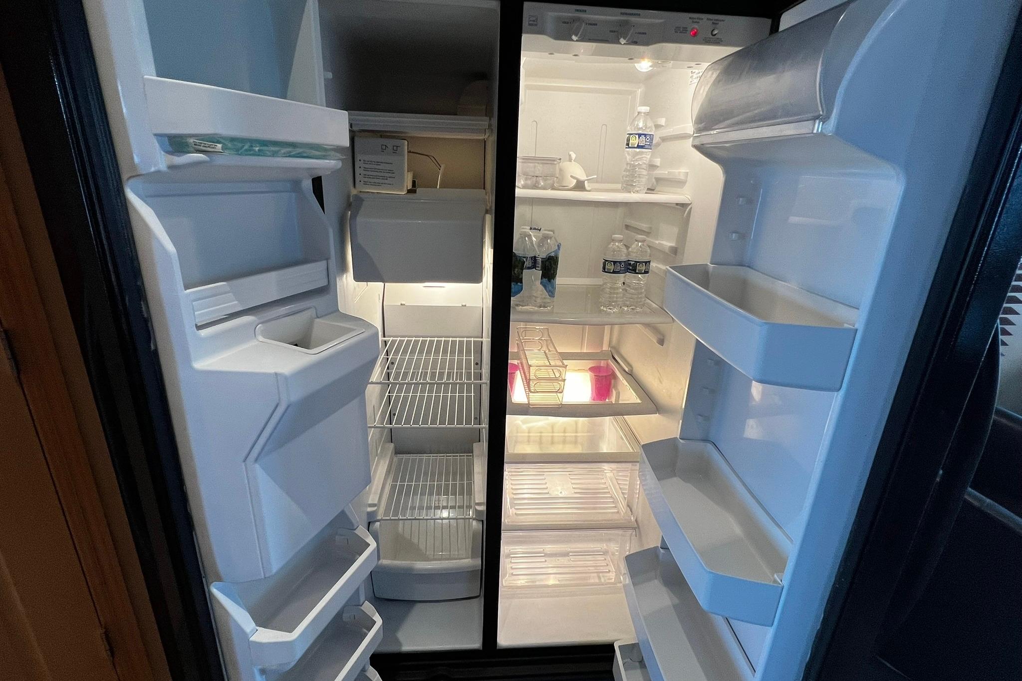 Open refrigerator on Skipperliner 480 Flybridge, showing shelves with bottled water and minimal items.