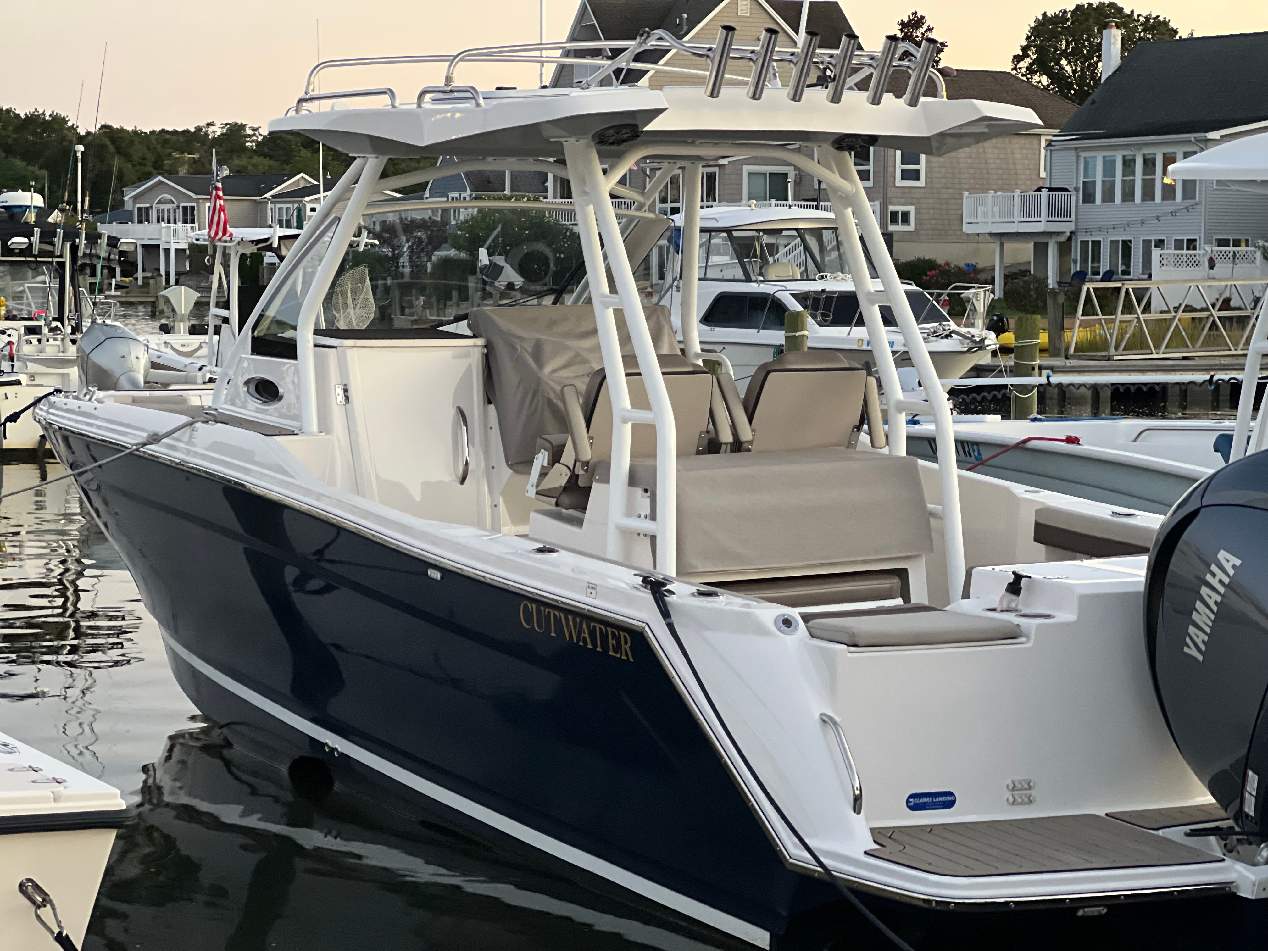 A 2022 Cutwater C-24 CW boat is on the water, surrounded by other boats and houses.