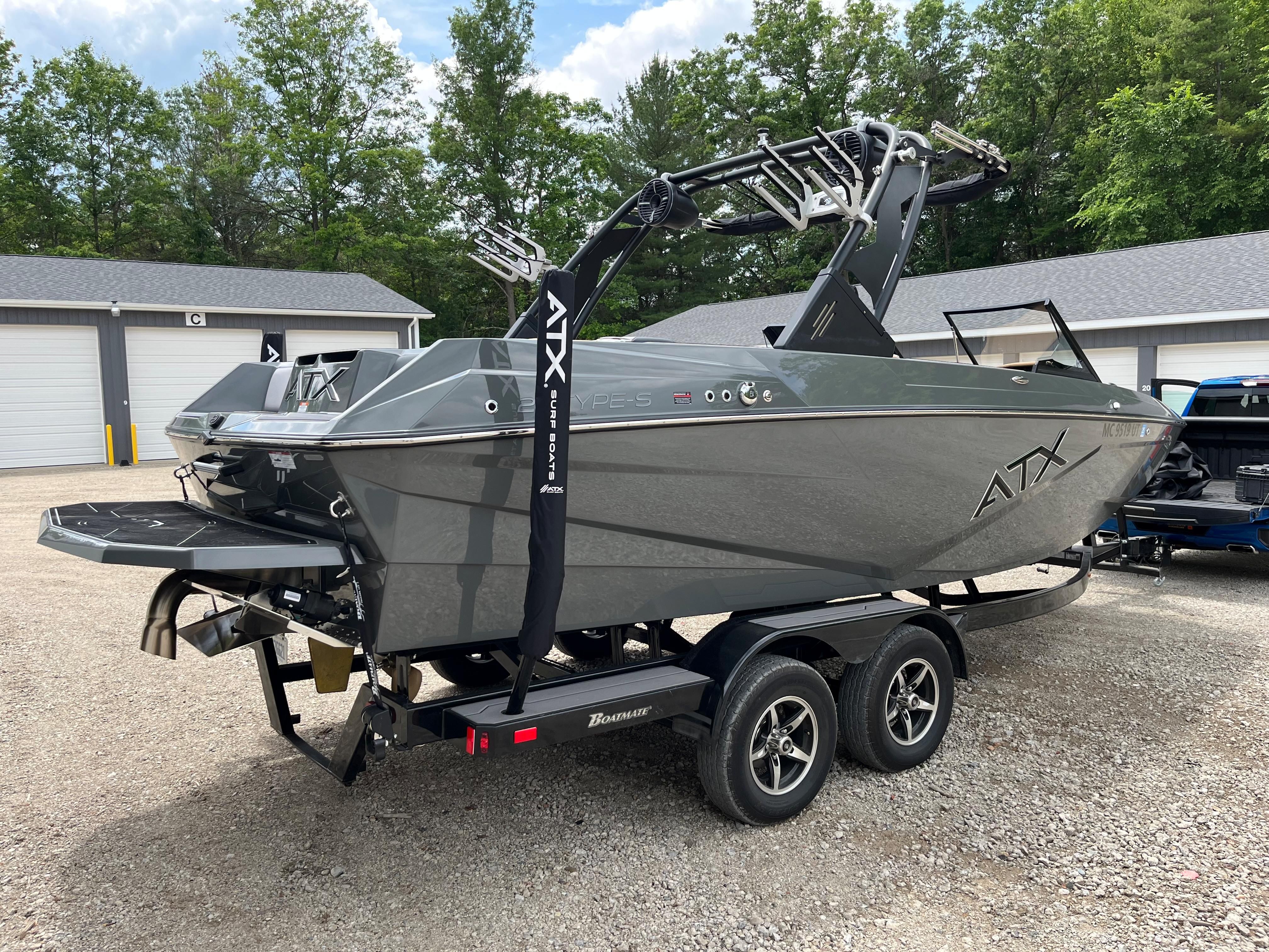 2022 ATX Surf Boats 22 Type-S on a trailer, surrounded by trees and garages.