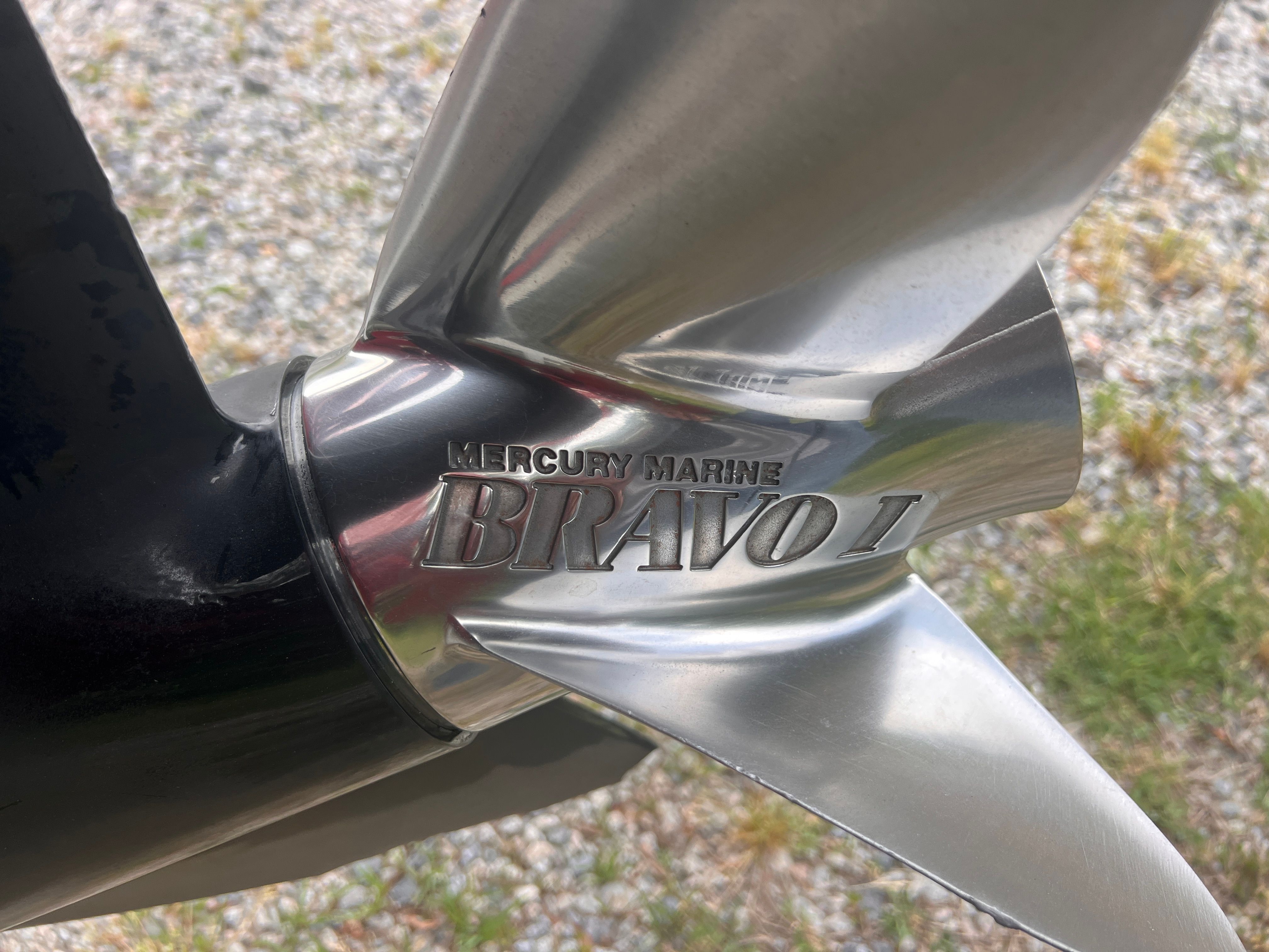 Close-up of a Mercury Marine Bravo I propeller on a gravel surface.
