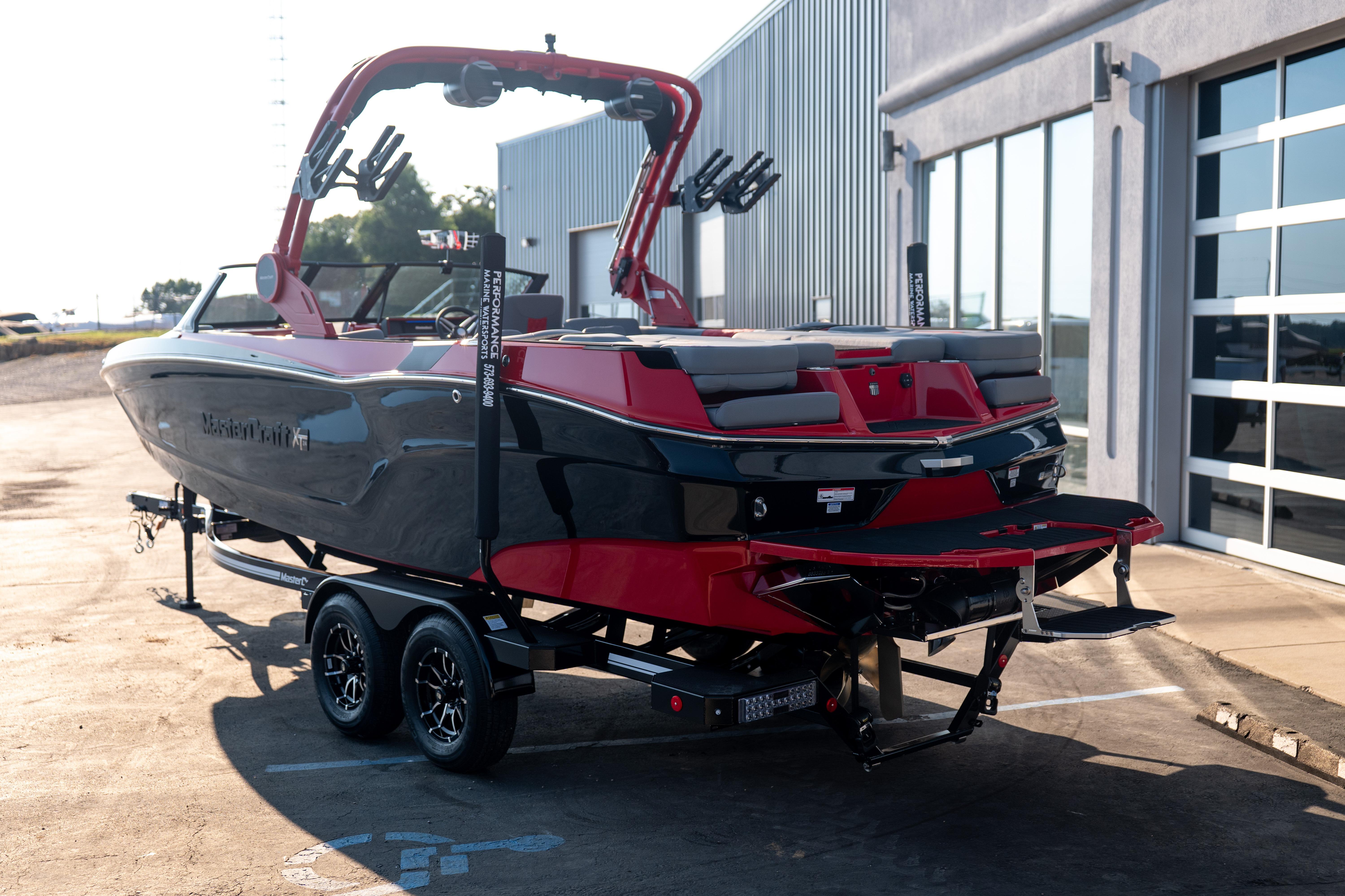 2027 MasterCraft XT24 boat on trailer, parked outside a modern building.
