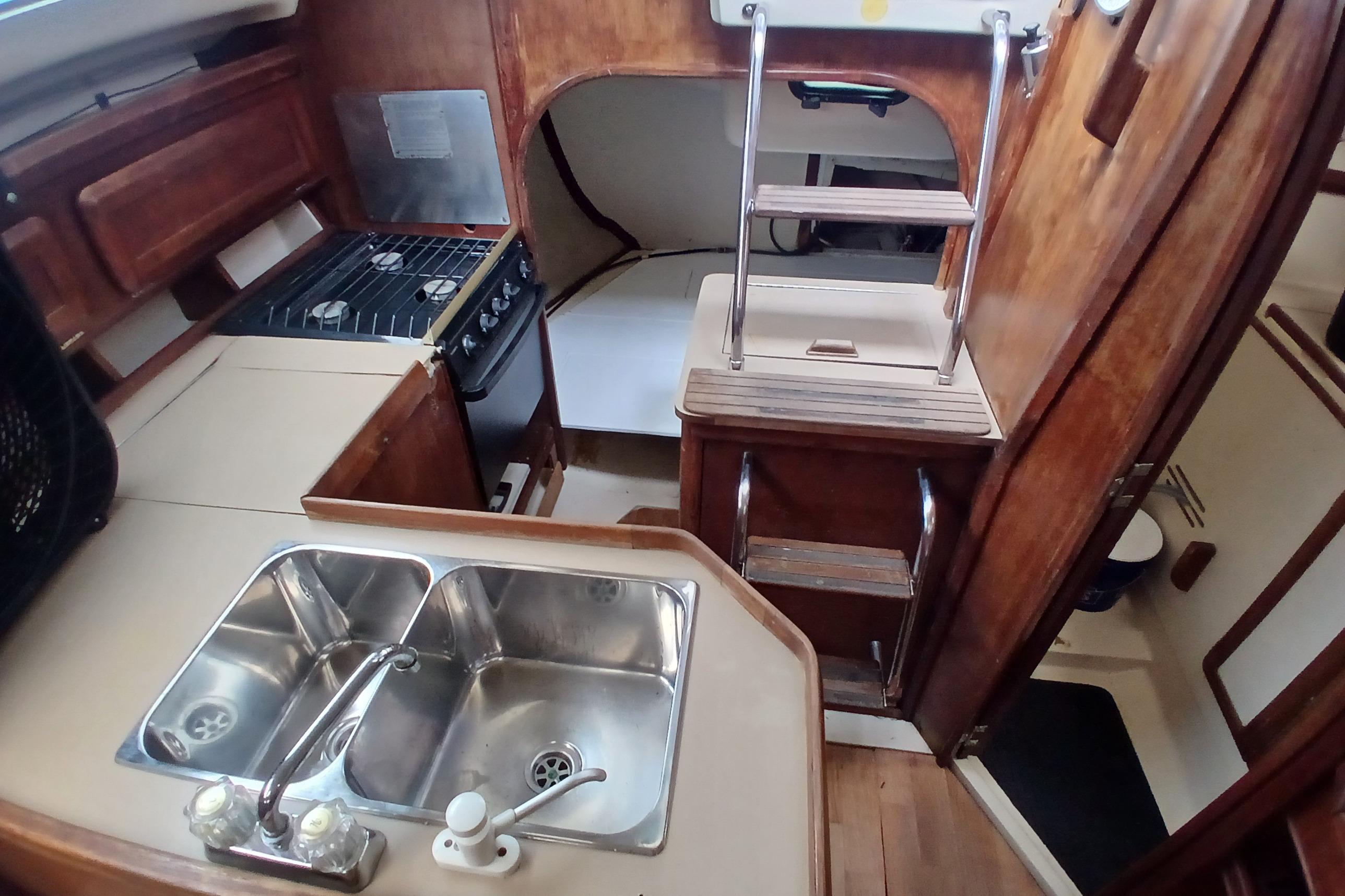Interior of a 1994 Hunter 30 sailboat featuring a compact kitchen and wooden cabinetry.