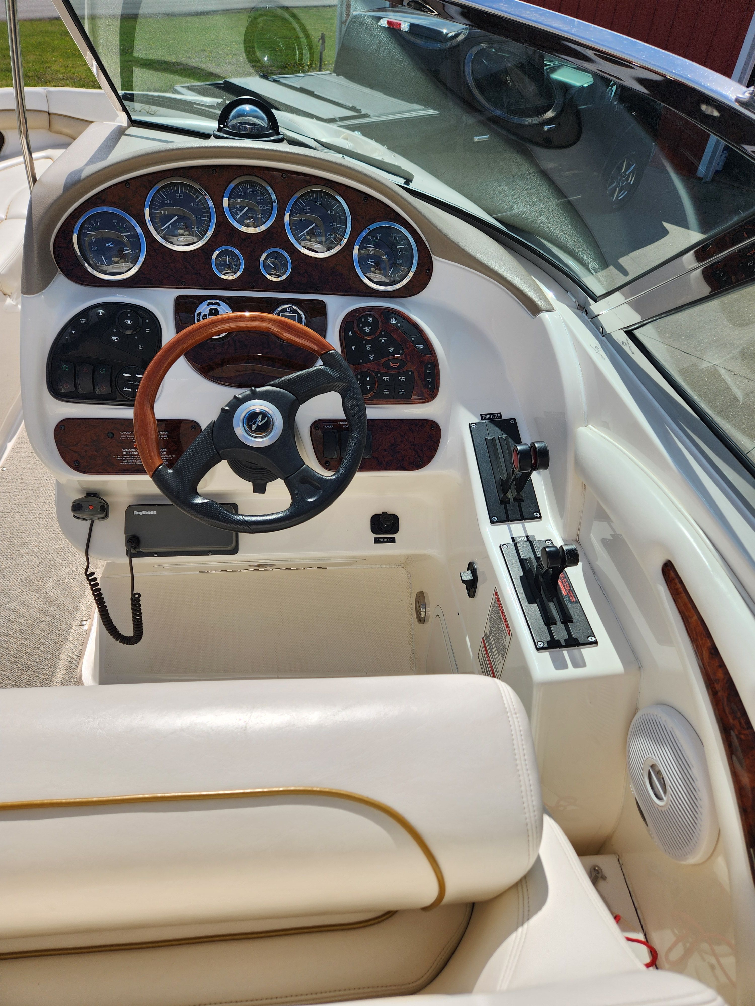 The cockpit of a Sea Ray 290 BR boat with a wooden steering wheel and instrument panel.