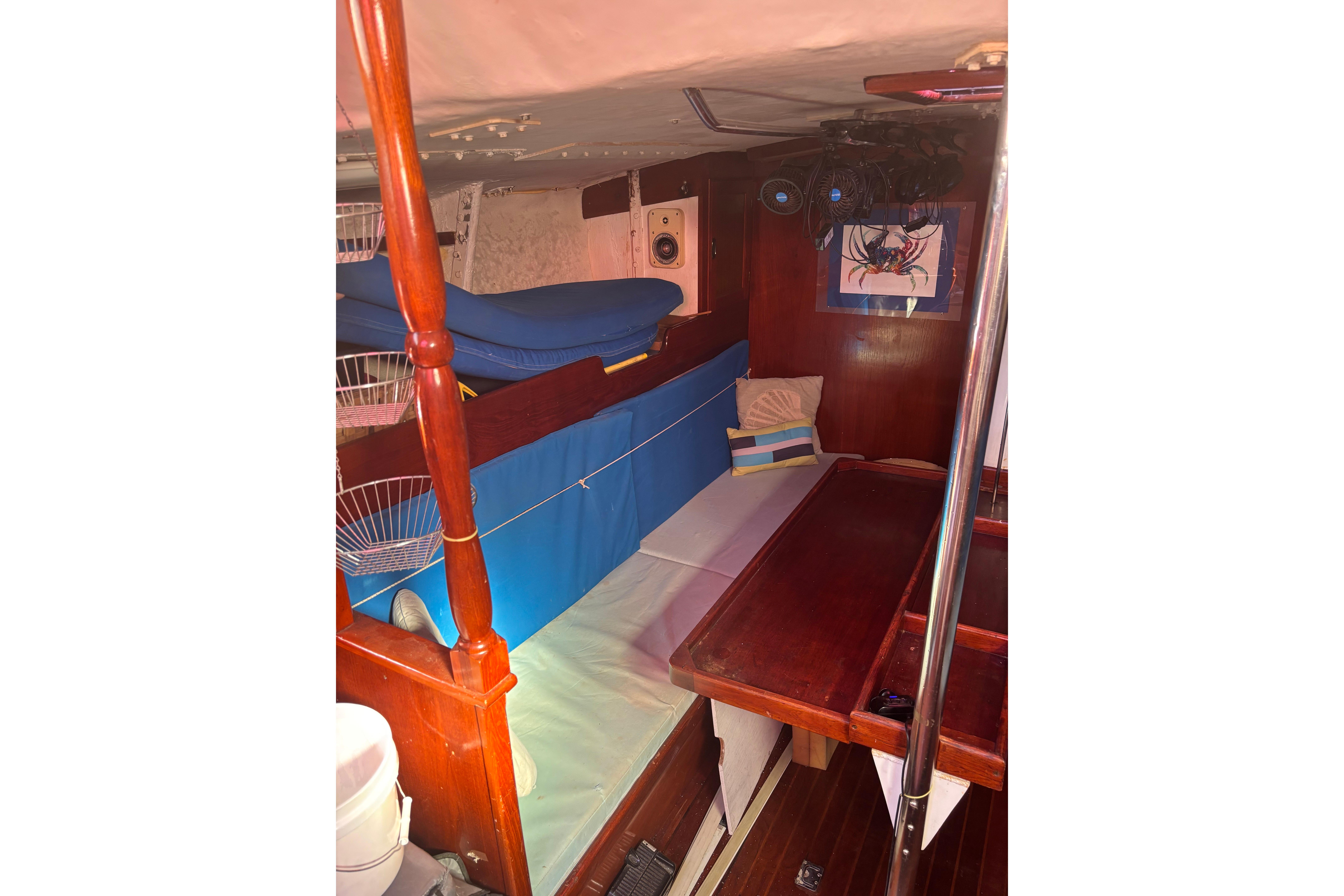 Interior of 1975 Columbia 52 sailboat with cozy wooden furnishings and blue accents.