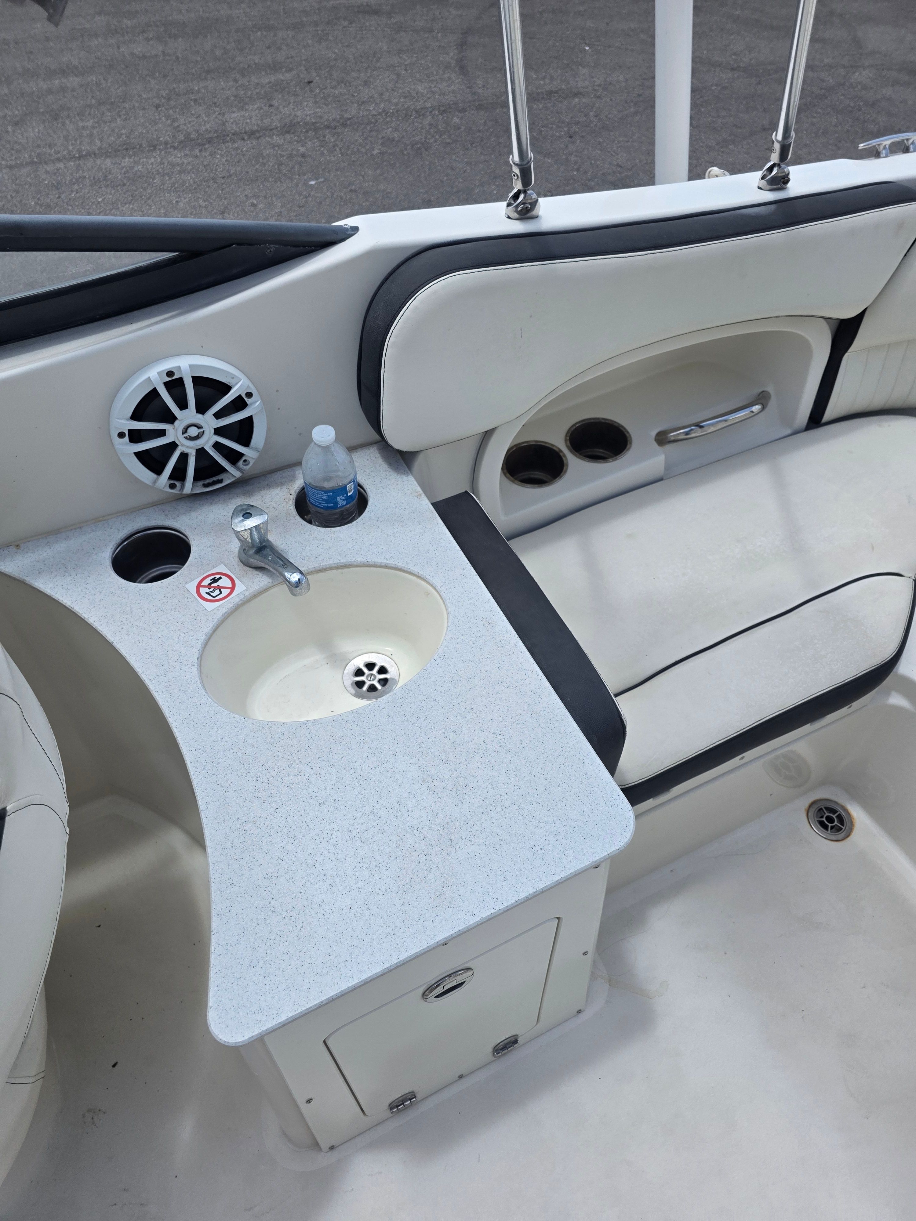 Interior of a boat with a sink, speaker, and cup holders.