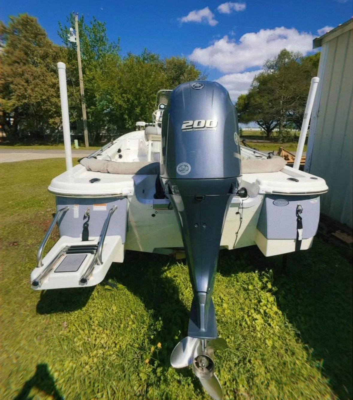 A 2022 Custom 215 XTS boat with a 200 HP outboard motor, parked on grass.
