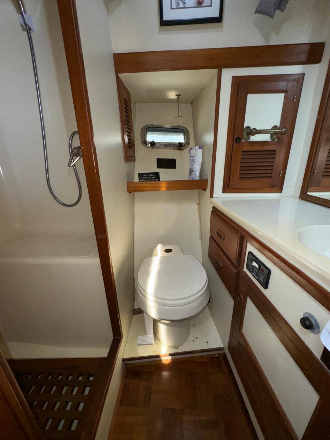 1987 Kadey-Krogen Silhouette yacht bathroom with shower, toilet, and wooden cabinetry.