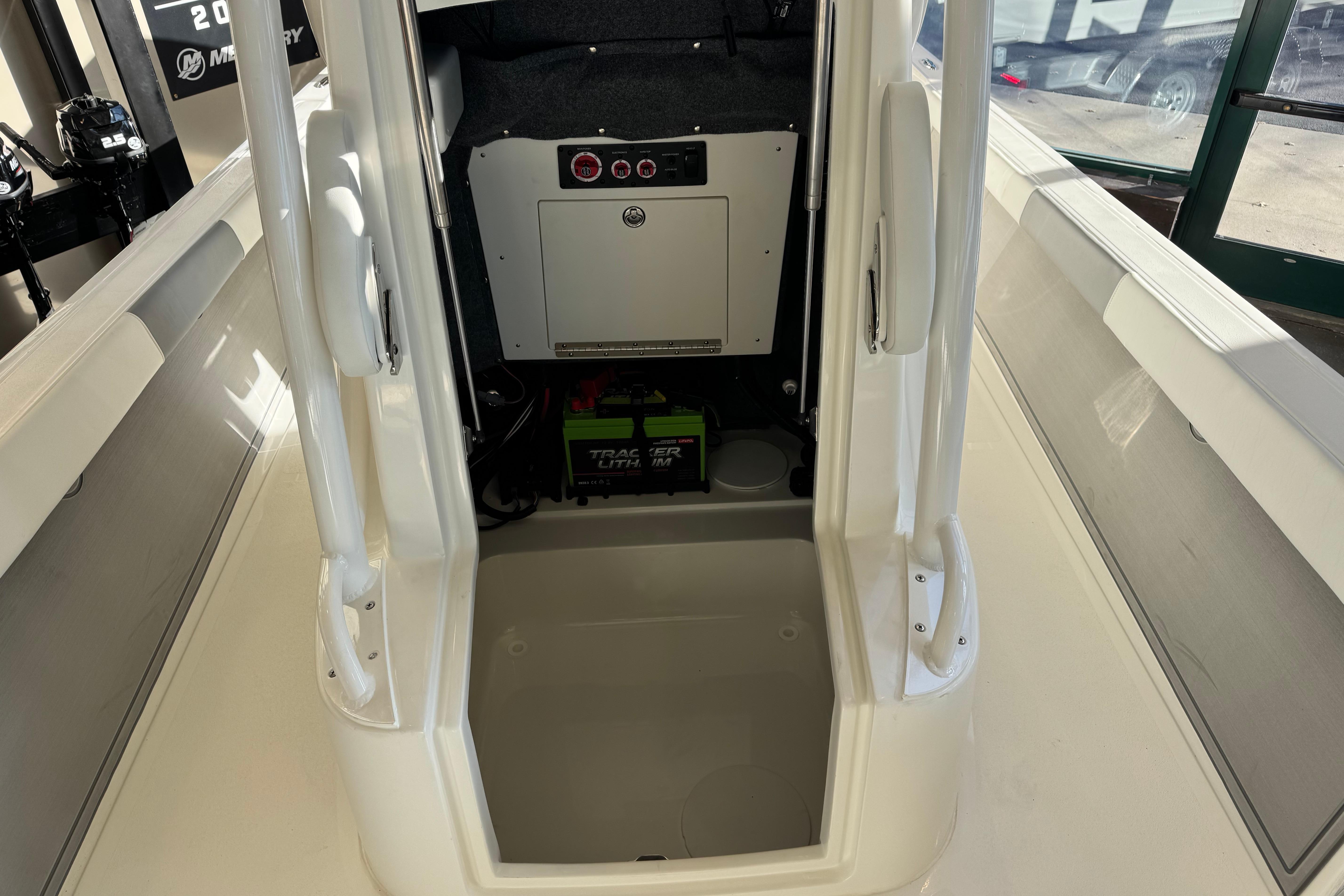 Interior view of 2026 Mako 24 APEX boat, featuring storage compartment and battery setup.