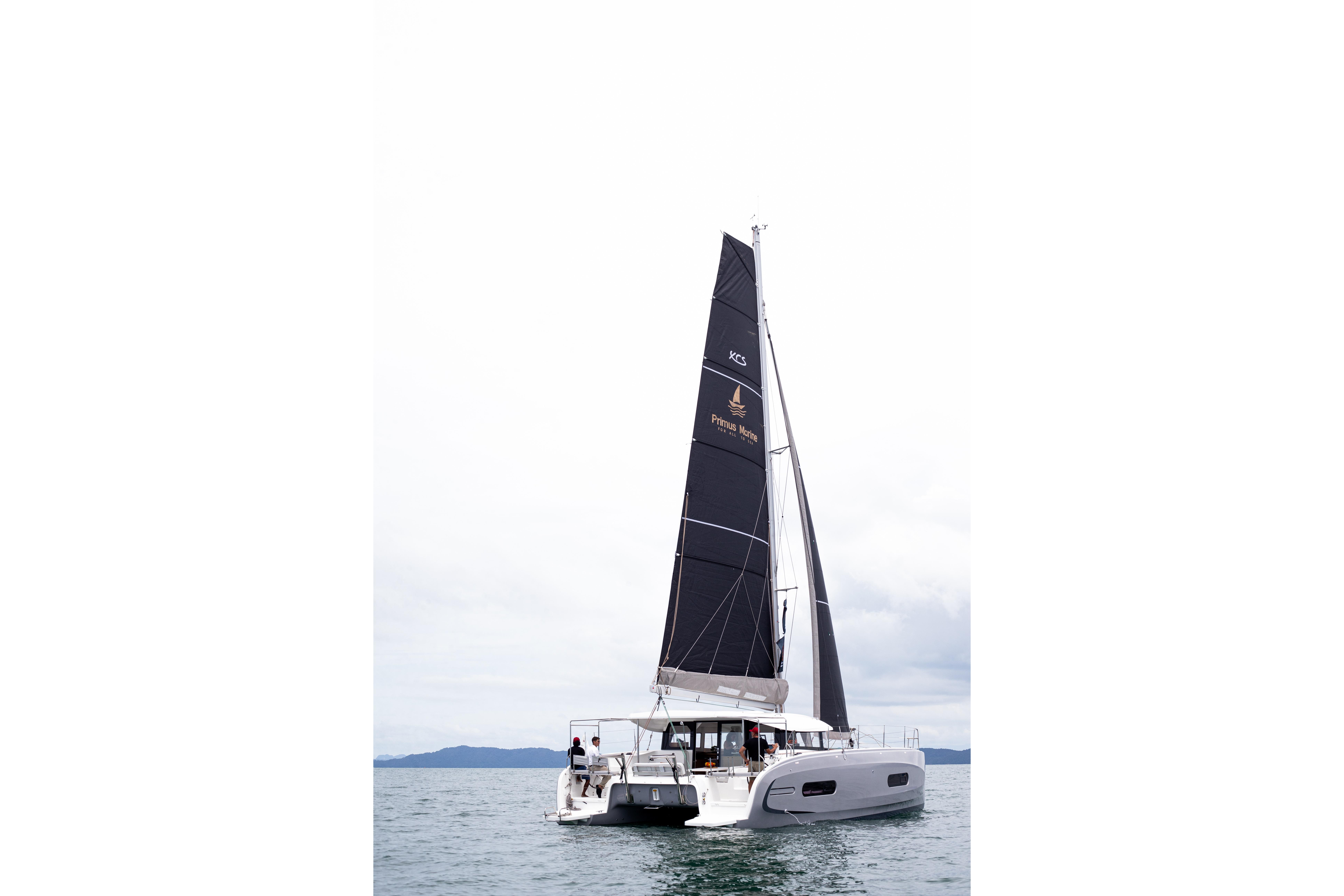 2025 Excess 11 catamaran sailing on open water with black sails.
