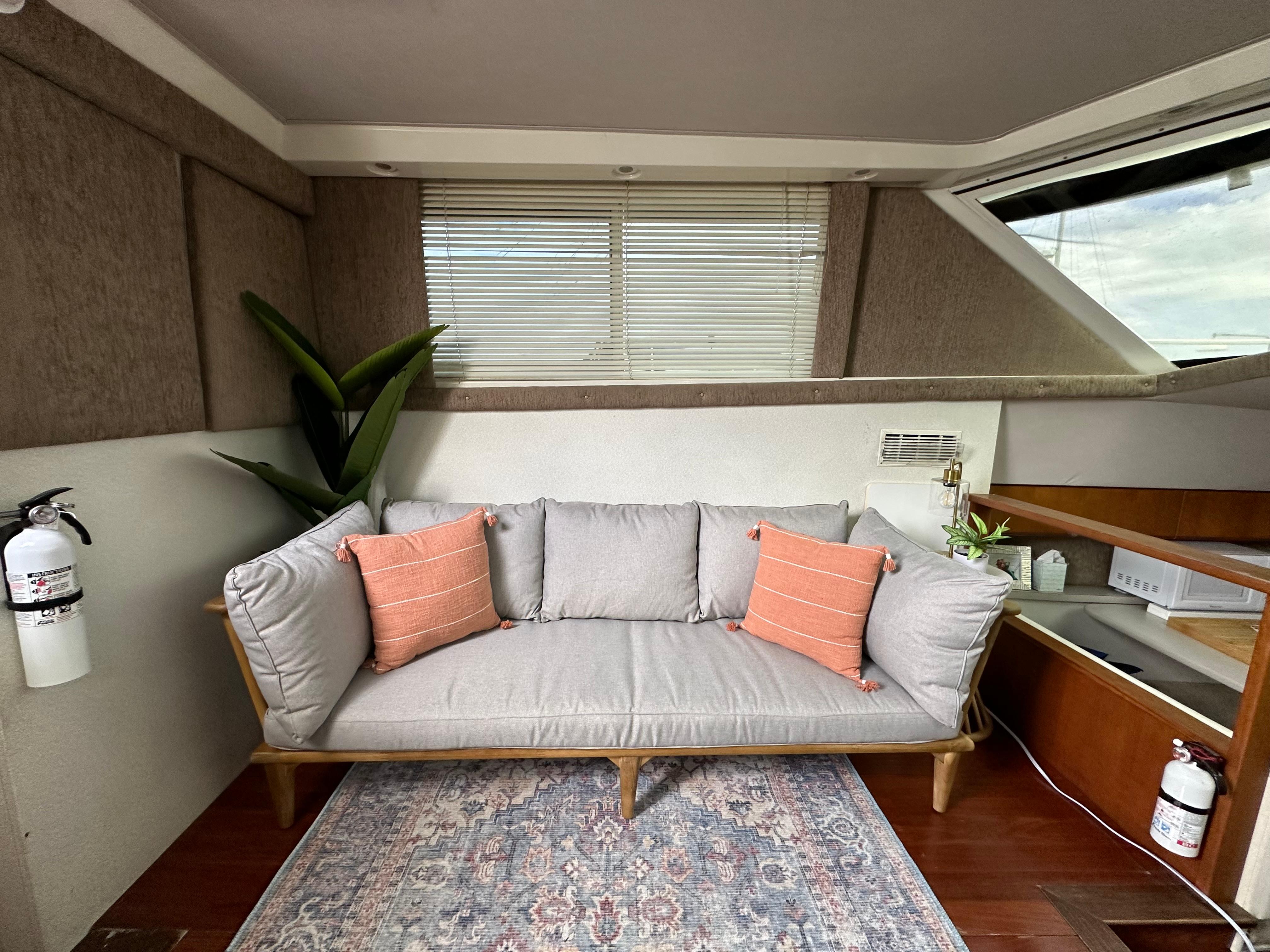 1995 Silverton AFT CABIN interior with gray sofa, orange pillows, and decorative plants.