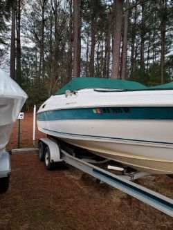 1996 Wellcraft 2400S boat on trailer in wooded area.