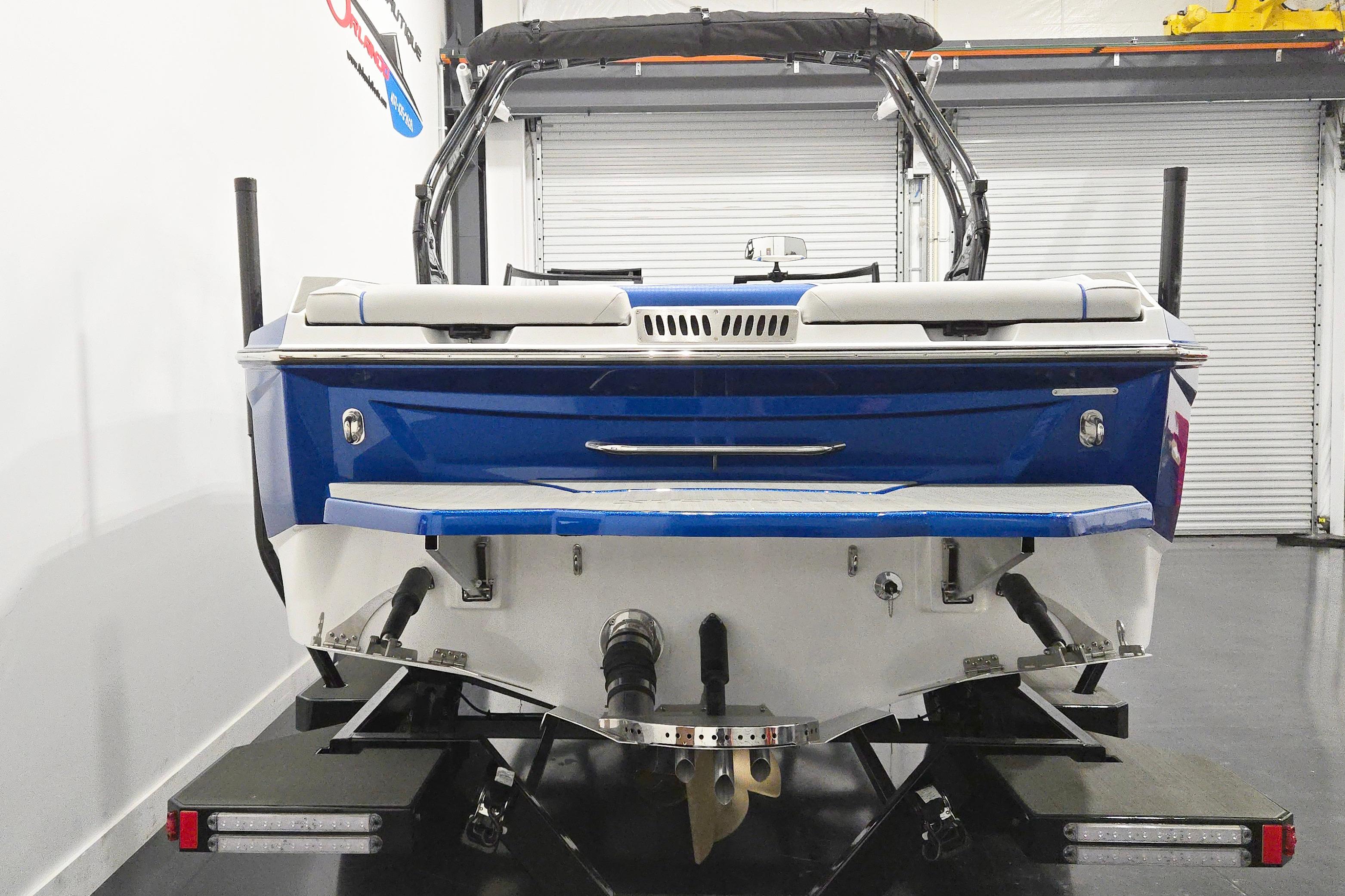 2026 Supreme S220 boat, blue and white, rear view in a garage setting.