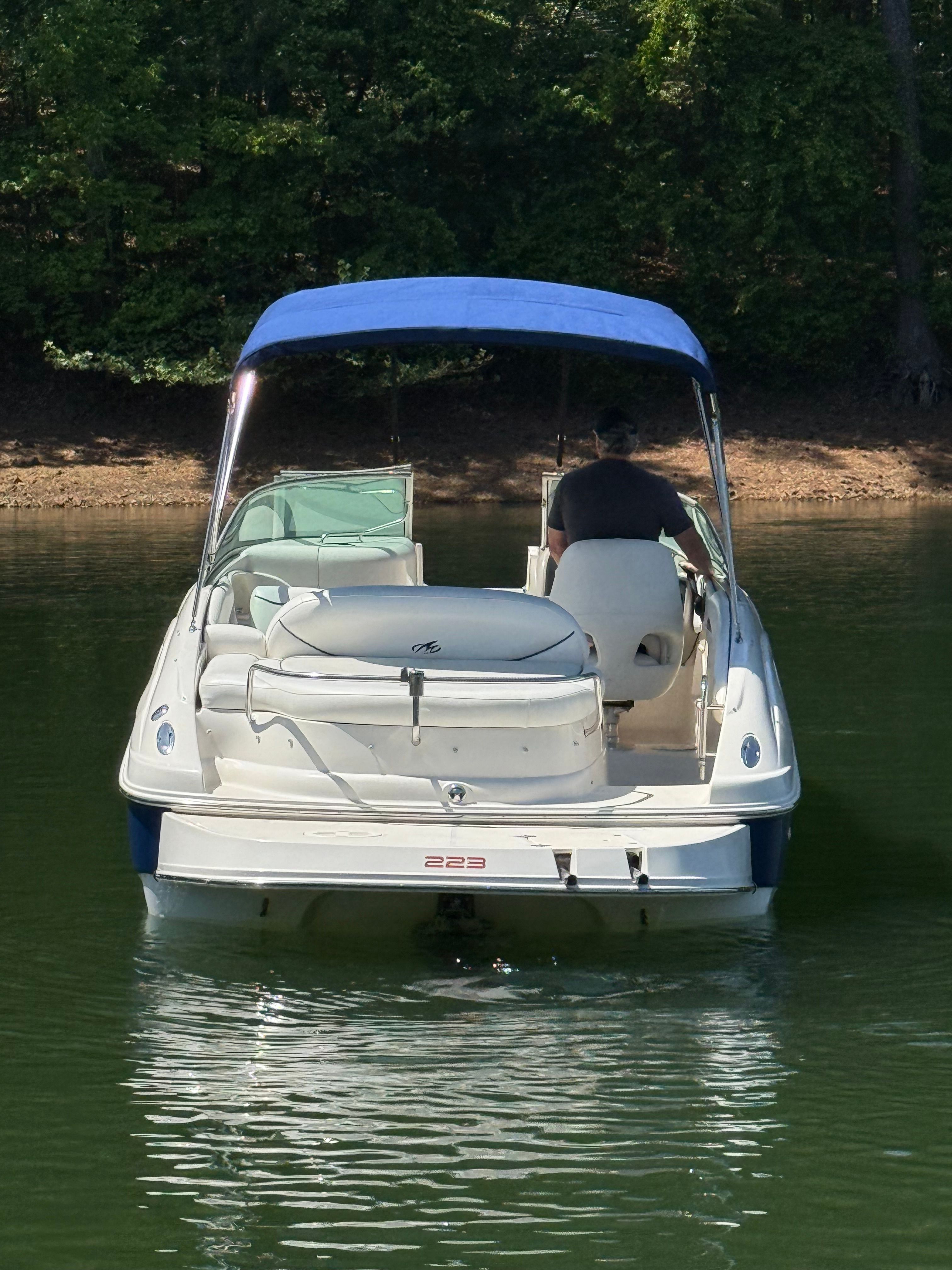 A white boat with a blue sunshade navigates a calm lake.