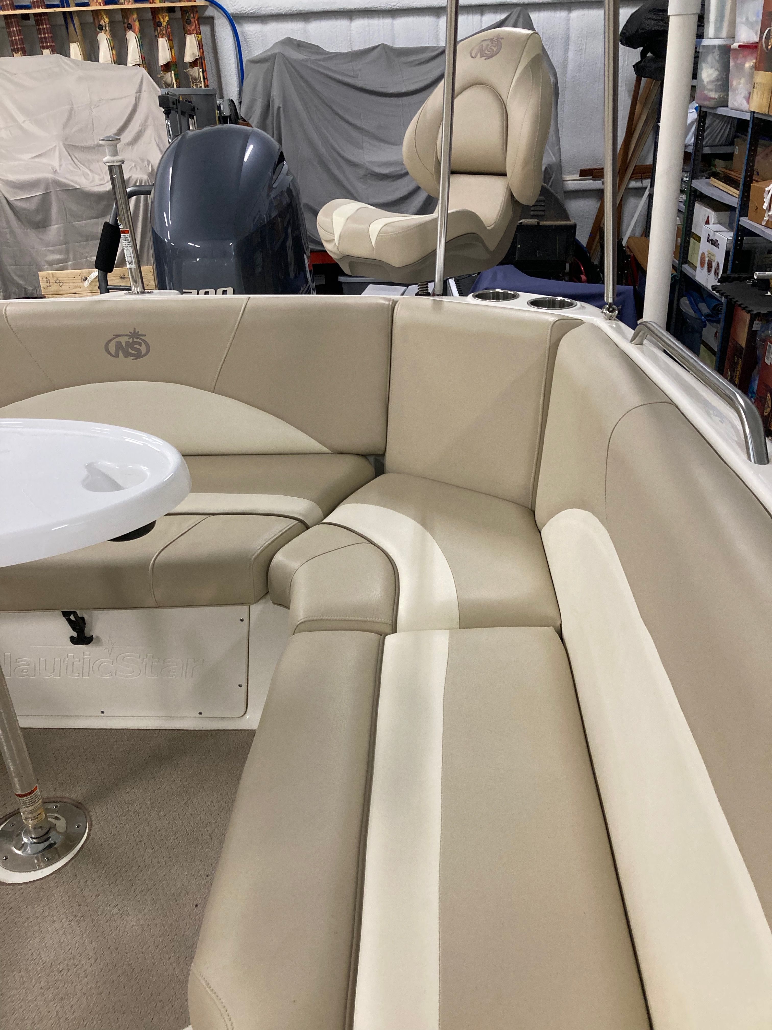 Boat interior with beige upholstered seating and a round table.