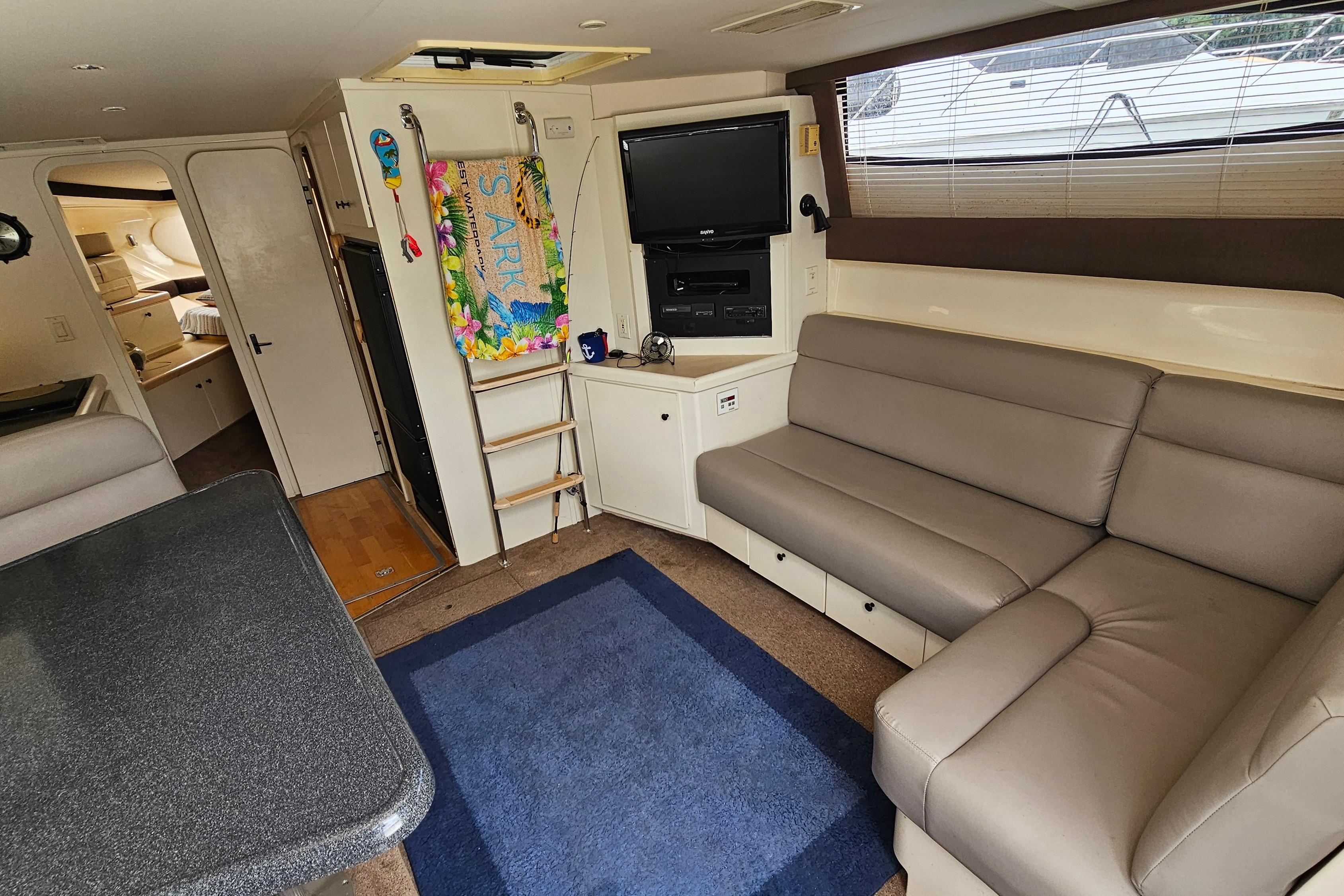 Interior of 1999 Carver 350 Mariner yacht with seating, TV, and ladder.