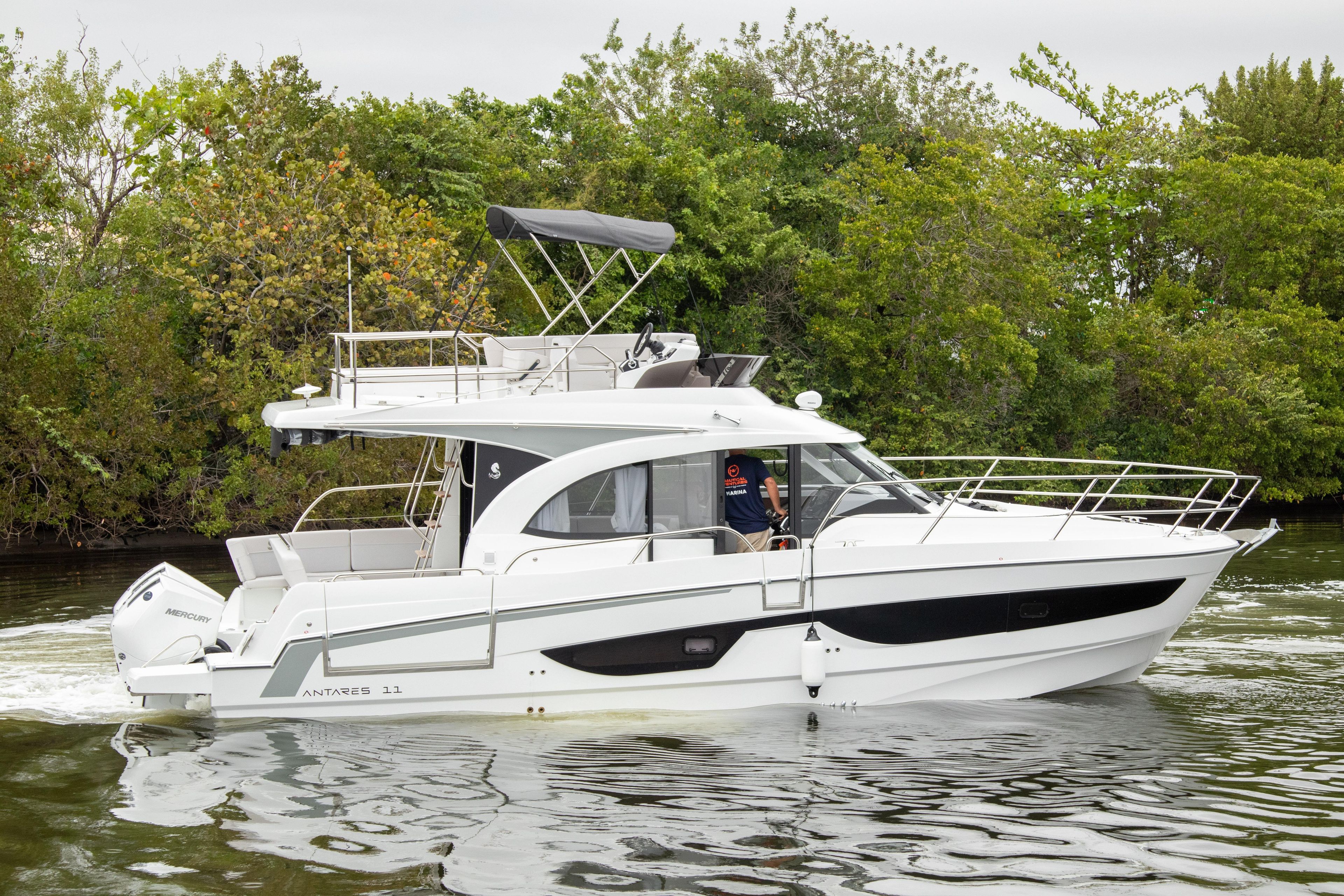 2026 Beneteau Antares 11 yacht cruising on a calm river with lush greenery.