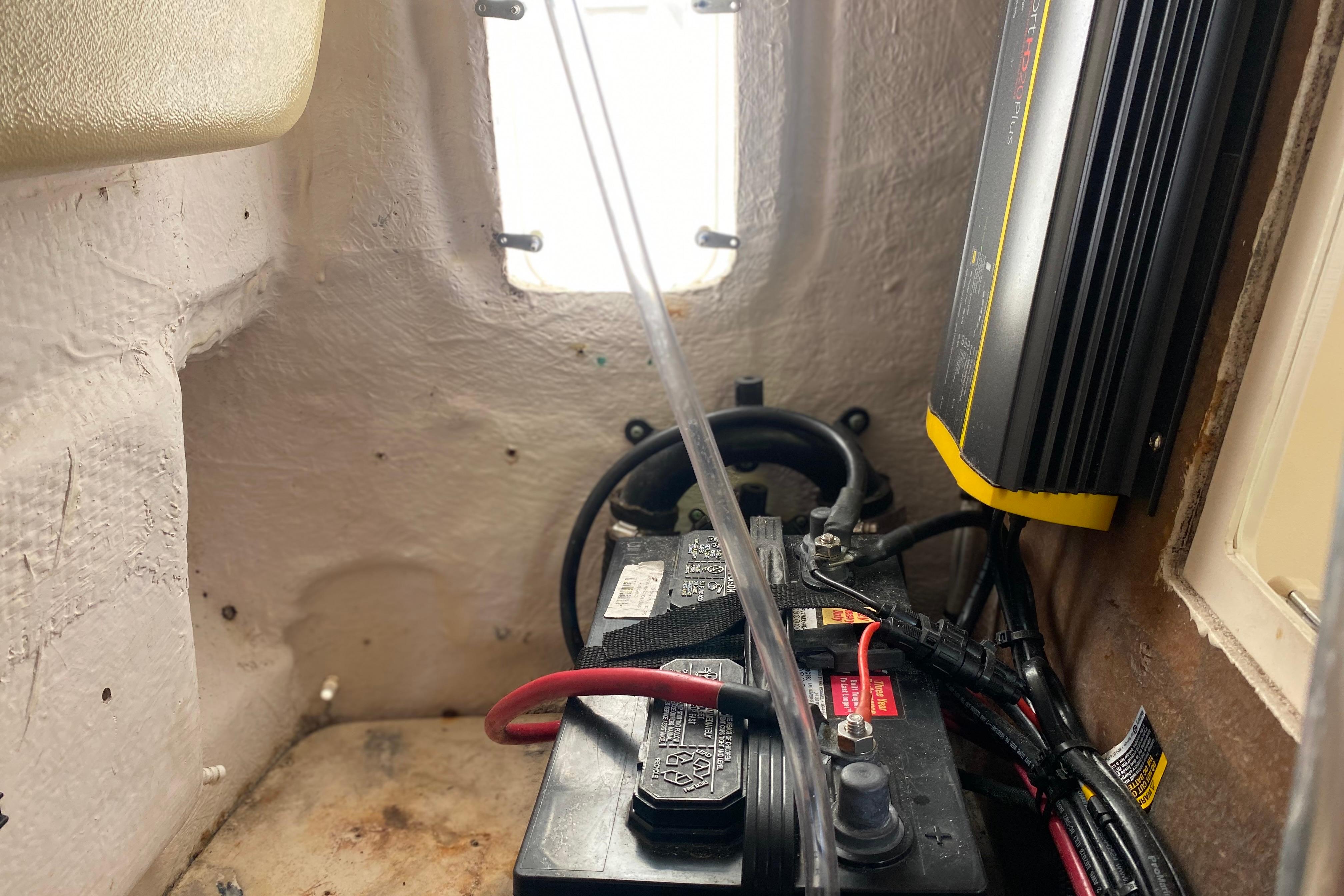 Battery compartment of a 2004 Grady-White Canyon 283 boat with wiring and charger.