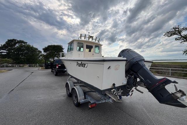 2003 Parker 2120 Sport Cabin boat on trailer, parked under cloudy sky.
