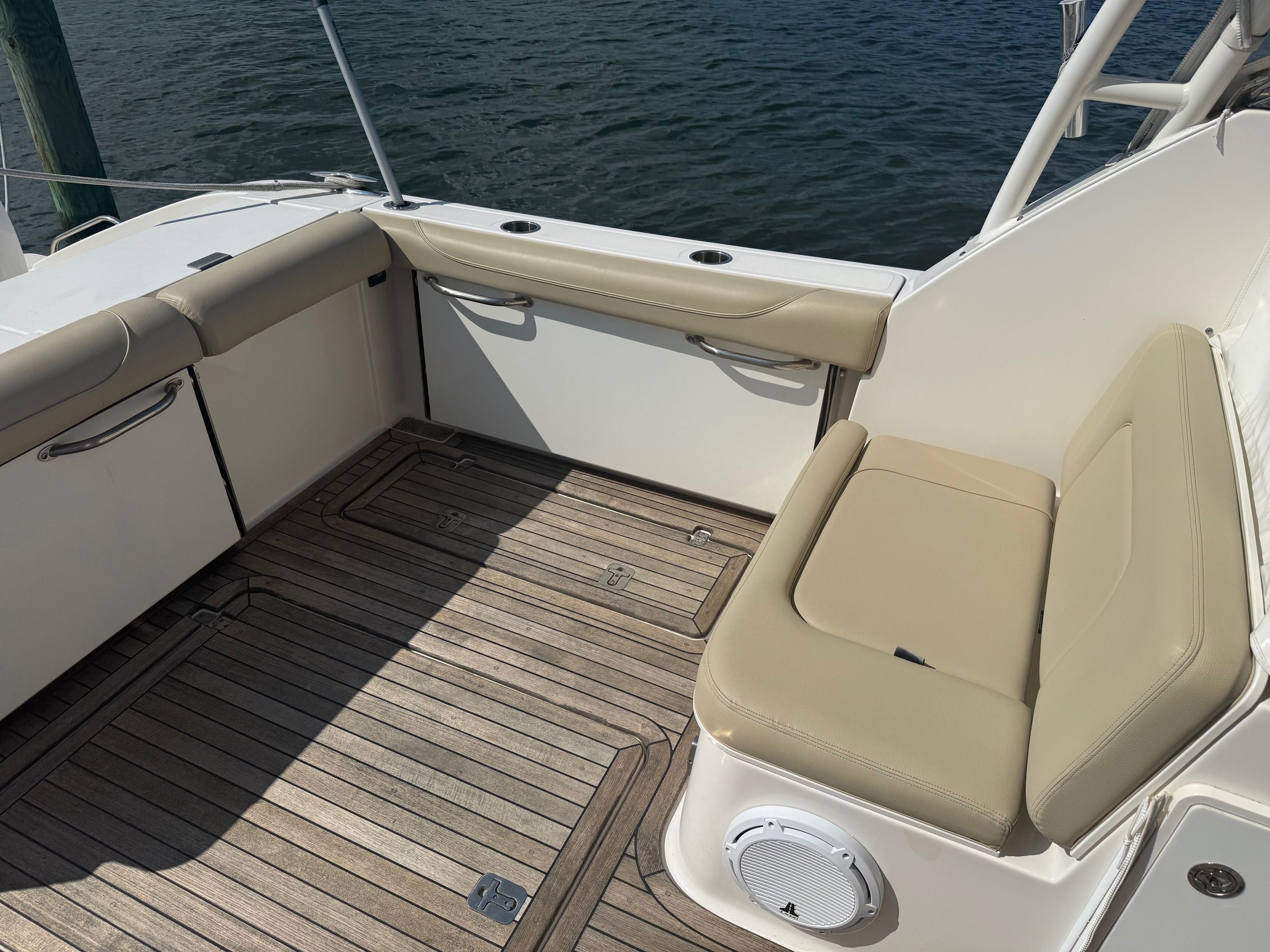 The image shows the cockpit of a 2016 Pursuit DC 325 Dual Console boat with beige seating and wooden flooring.