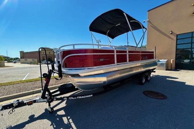 2026 Sun Tracker Fishin' Barge 22 DLX pontoon boat on trailer, parked outdoors.