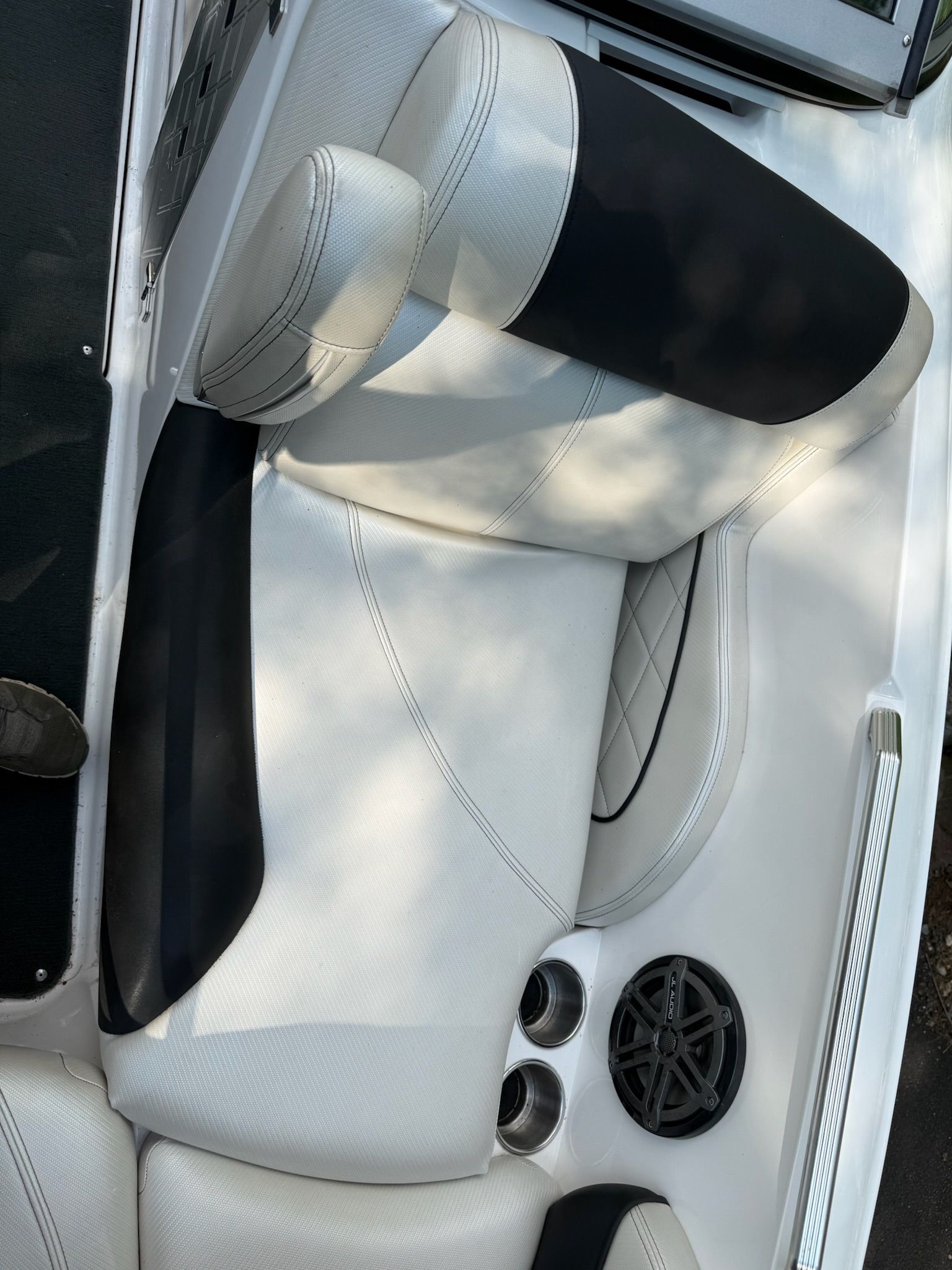A sleek seating area with white and black upholstery, speaker, and cup holders.