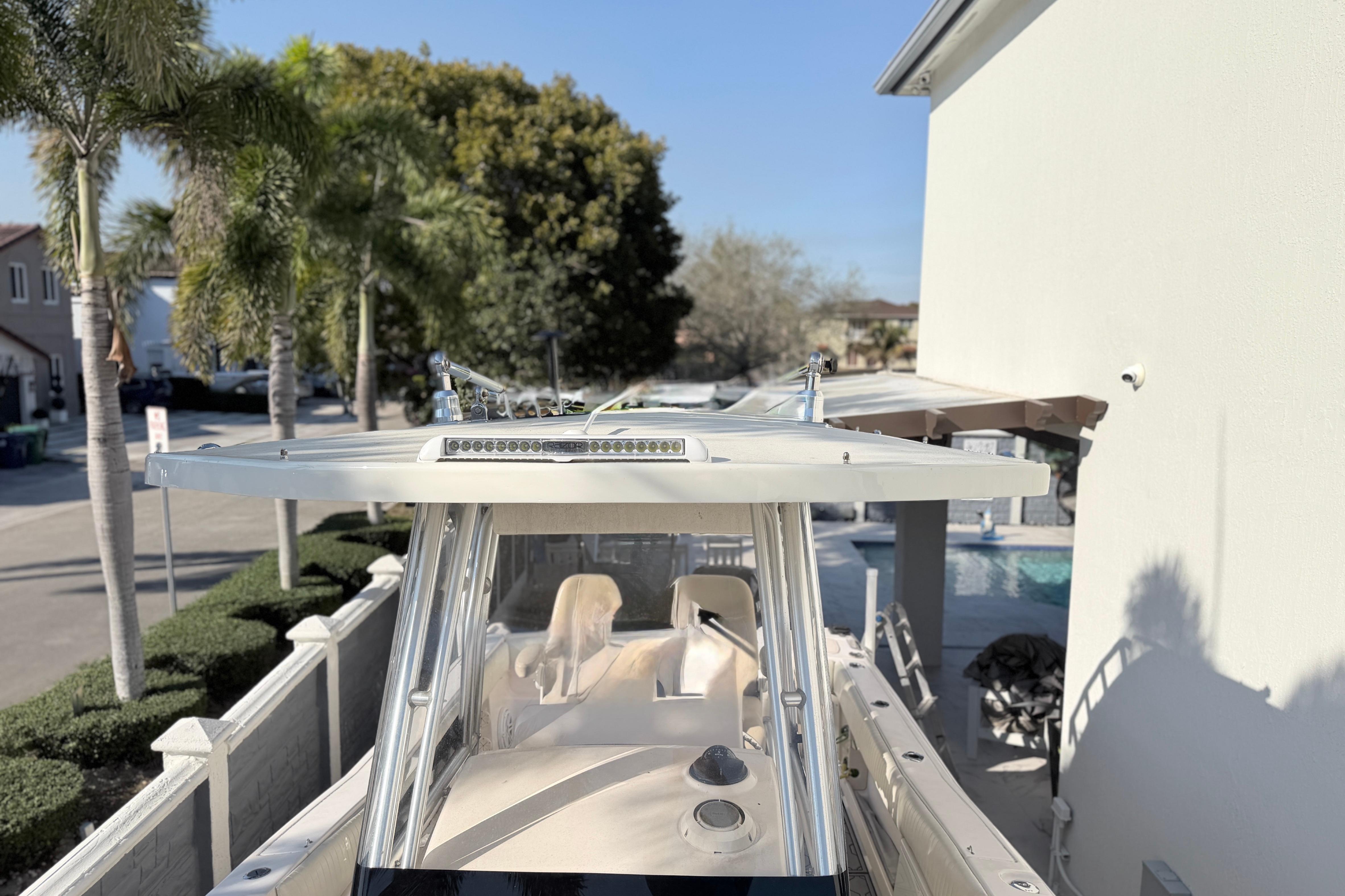 2004 Grady White 273 boat docked near palm trees and a poolside area.