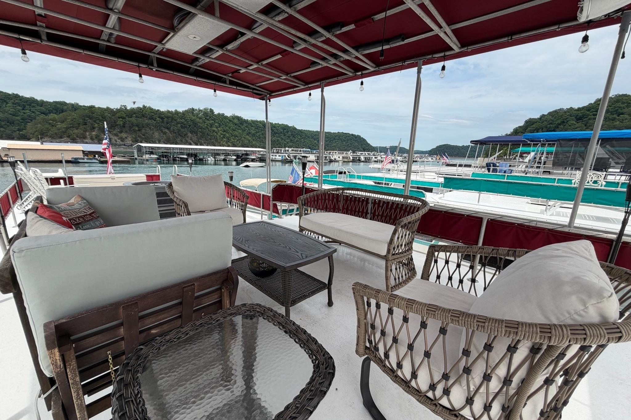 Outdoor seating on a 1987 Sumerset 14x60 houseboat, docked with scenic lake views.