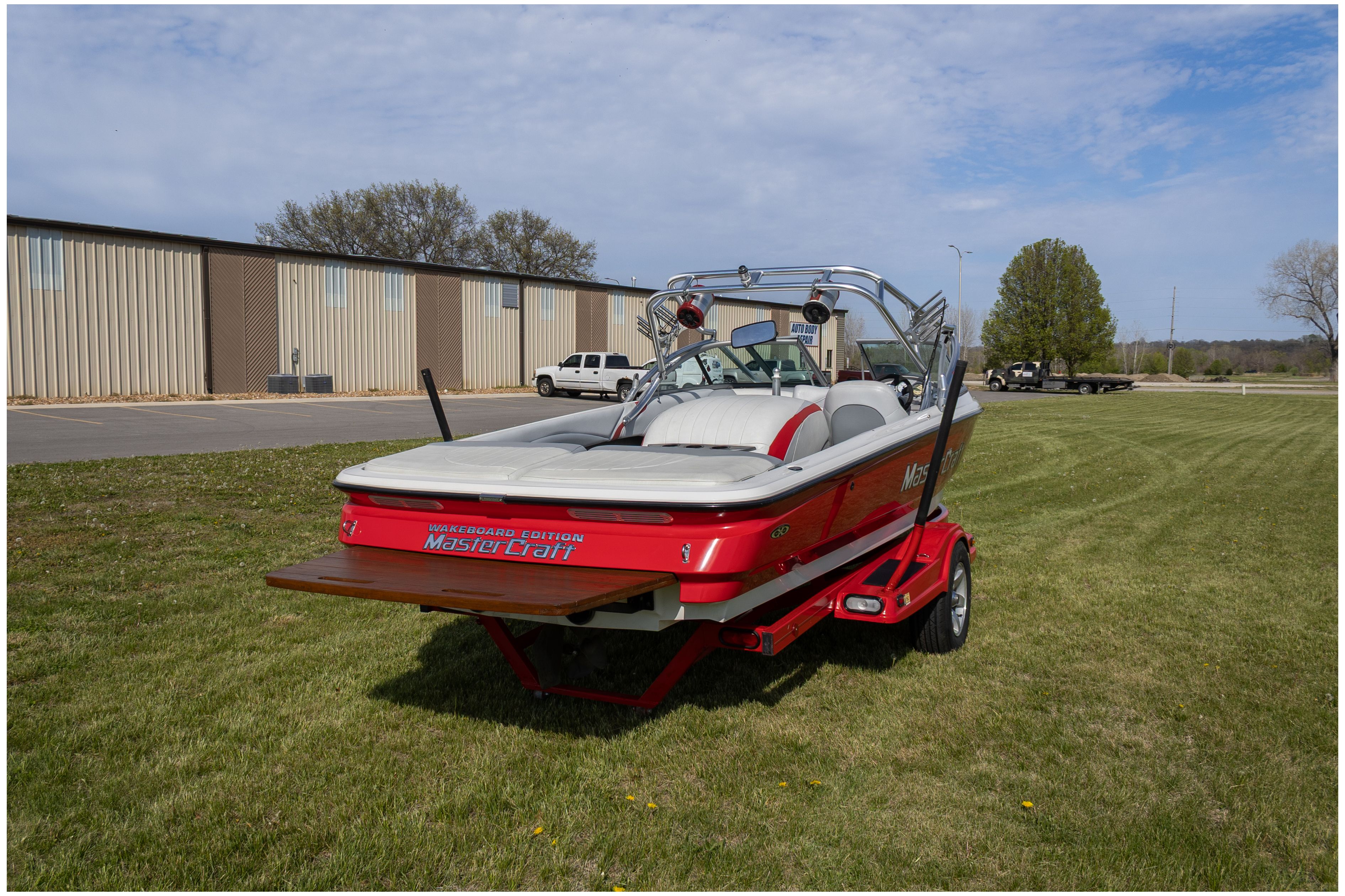 Red 2002 MasterCraft X-7 boat parked outdoors on trailer.
