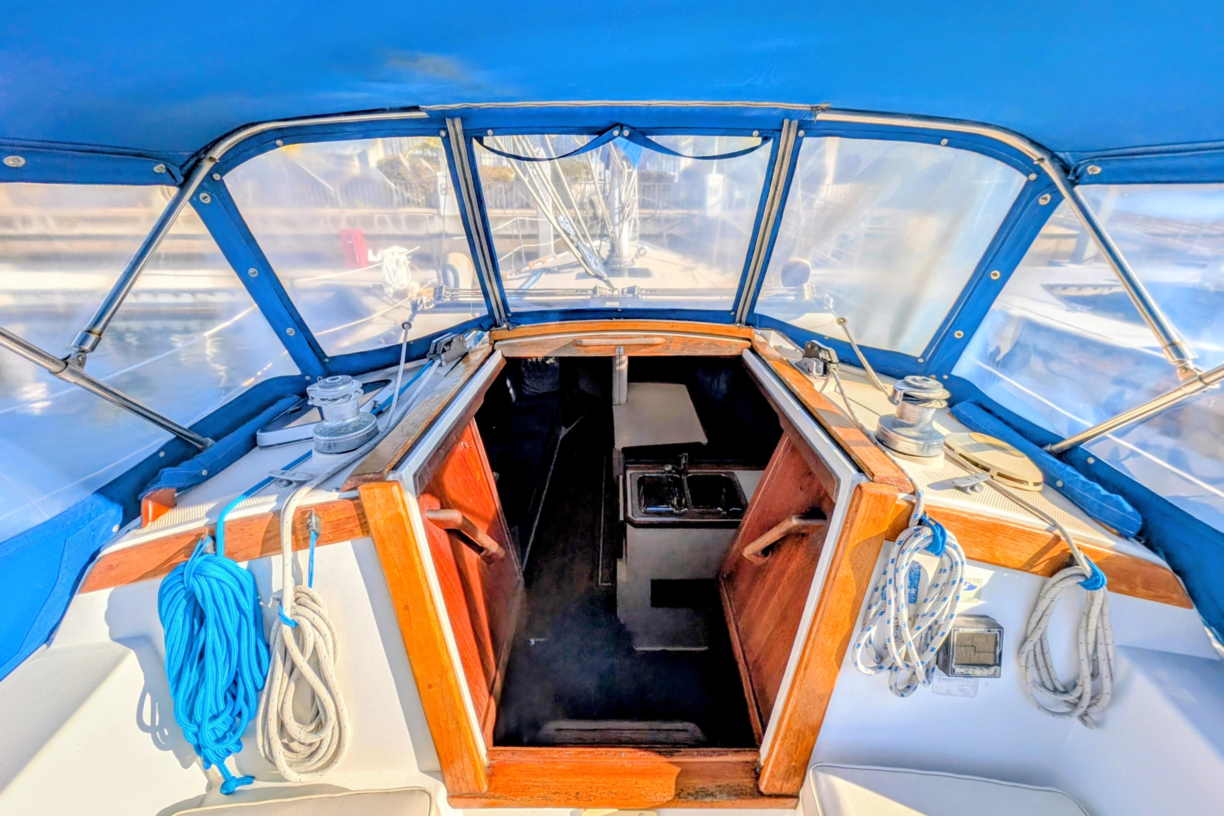 1989 Catalina 34 sailboat cockpit with blue canopy and wooden hatch entrance.