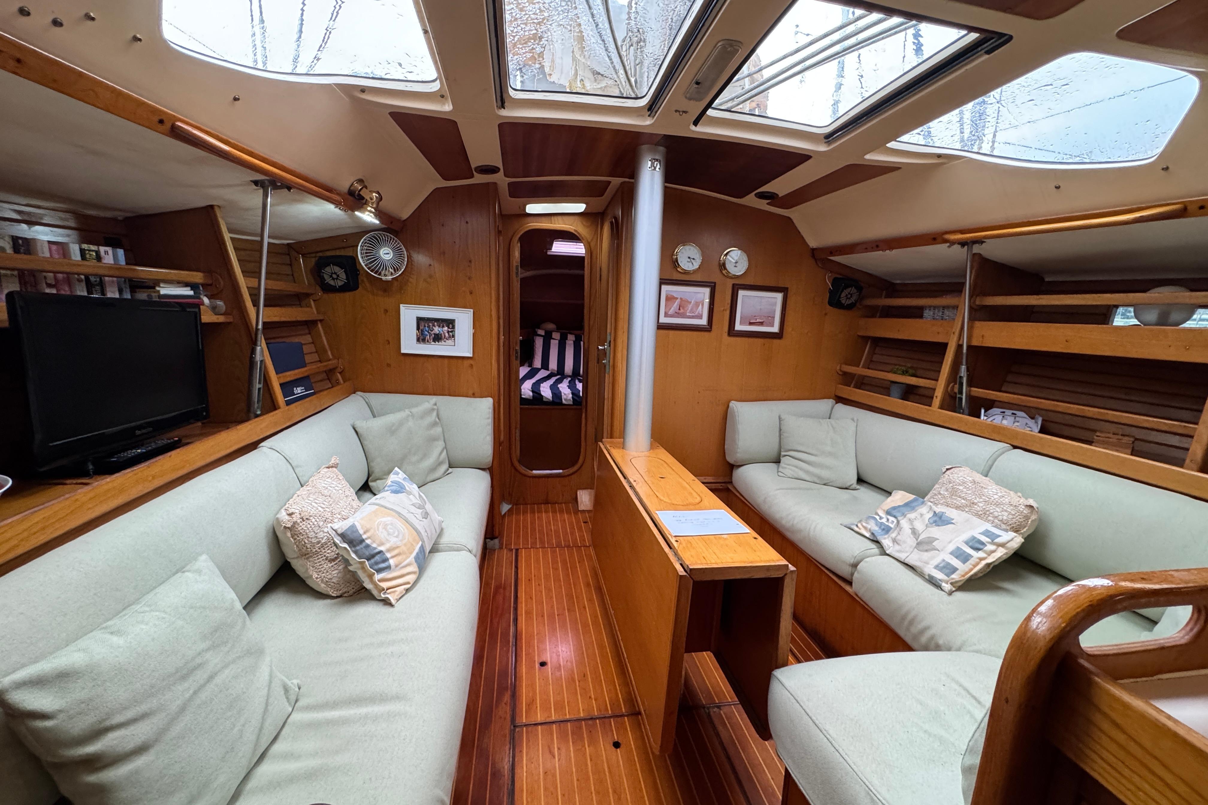 Interior of 1988 Beneteau Oceanis 390 sailboat with cozy seating and wooden finishes.
