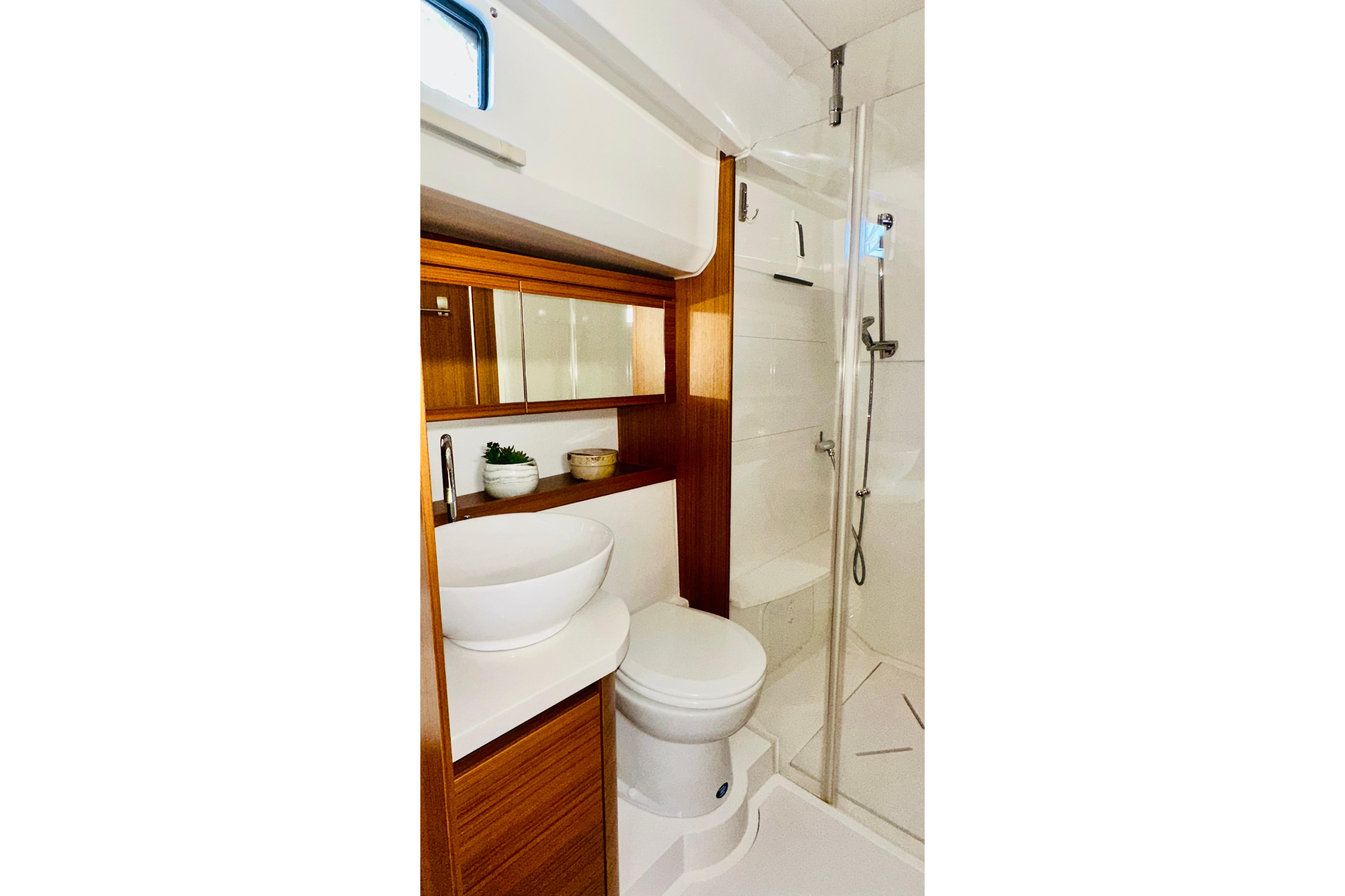Modern bathroom in 2021 Greenline 39 Hybrid yacht with wood accents and glass shower.