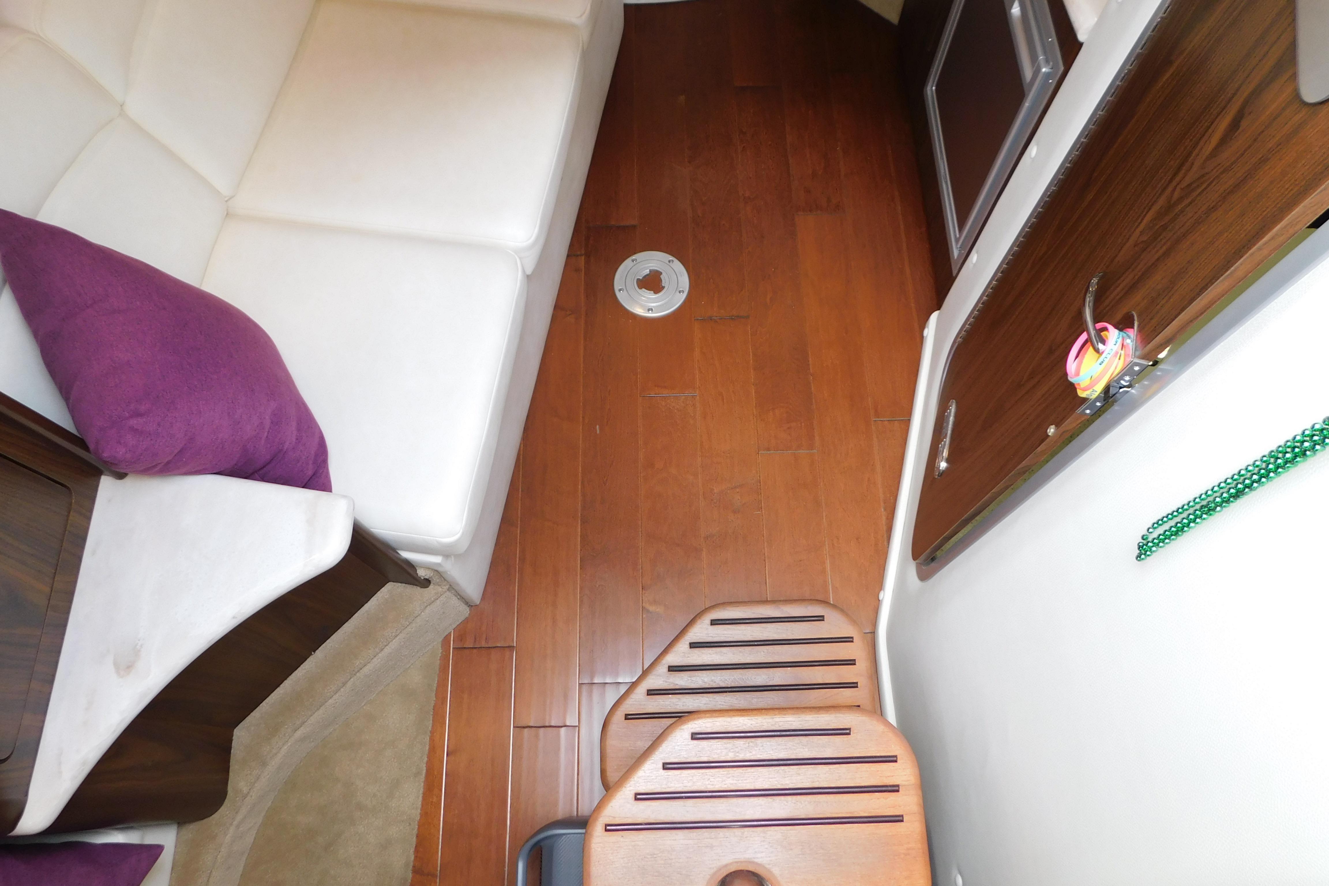 Interior of 2017 Rinker EX 320 boat with wooden flooring and white seating.