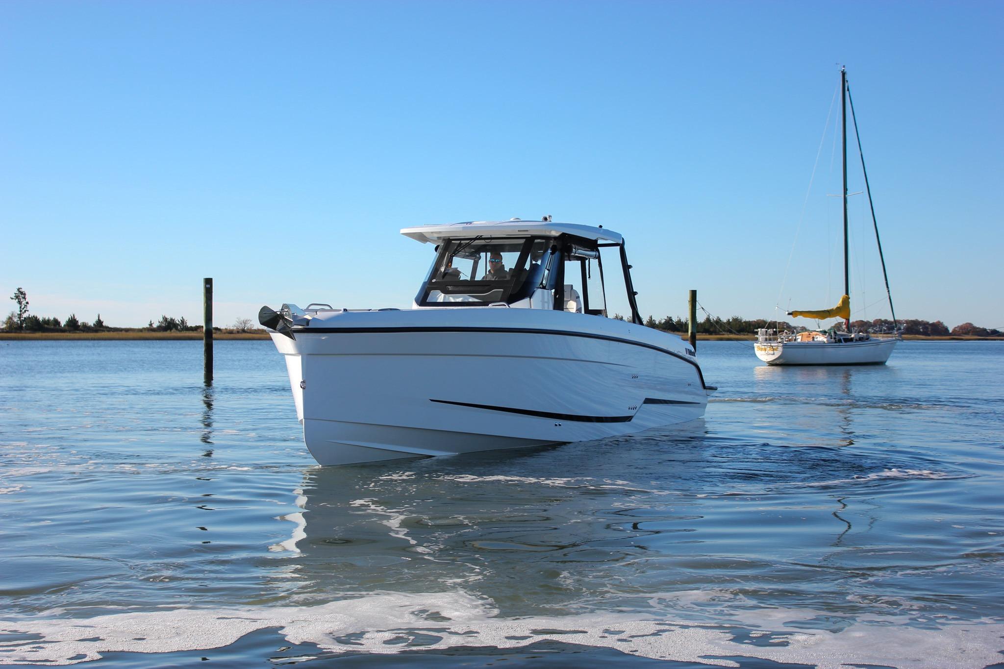 2026 Wellcraft 38 T-Top boat on calm water with sailboat in background.