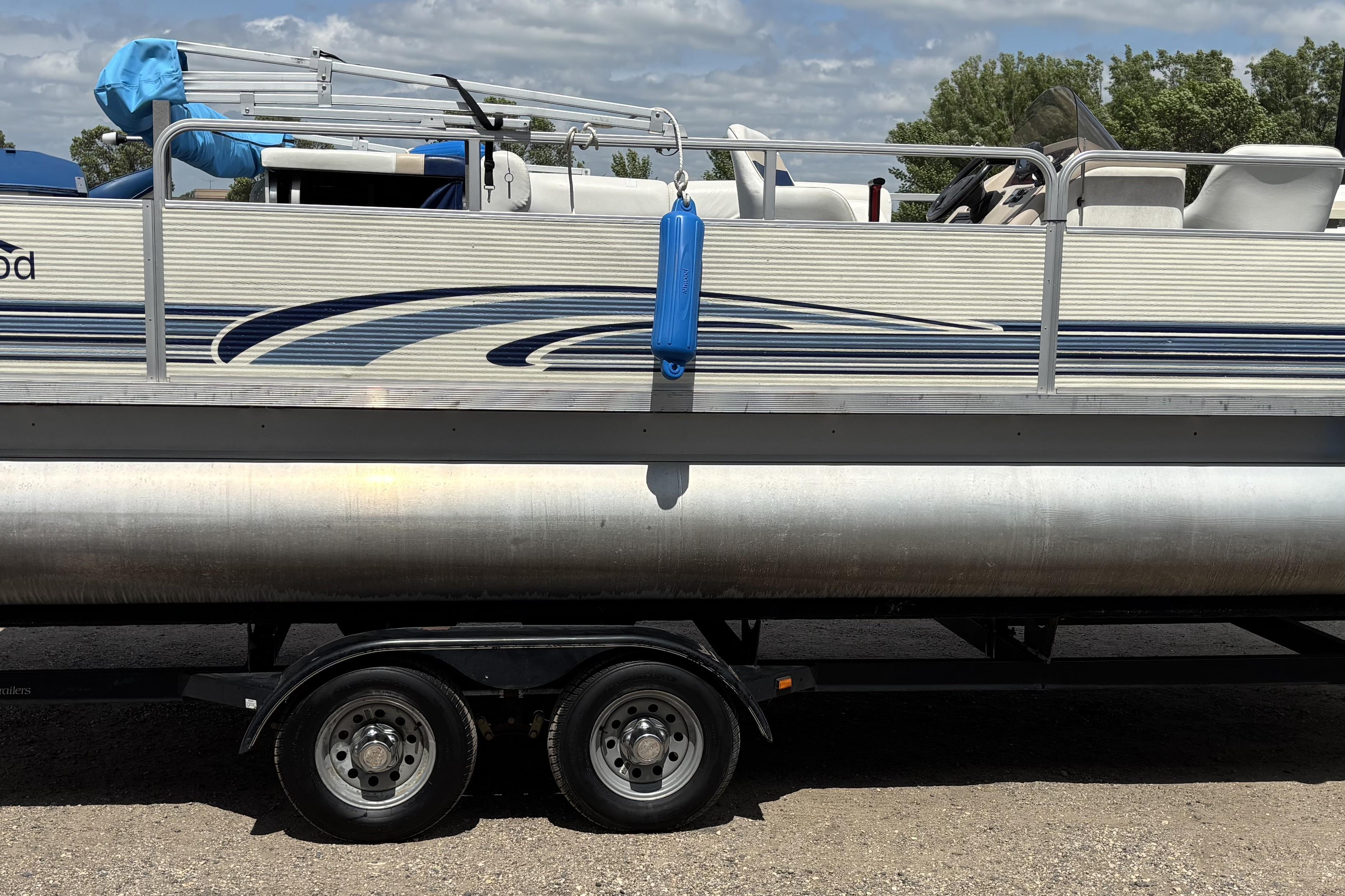1997 Northwood 24' Pontoon boat on trailer, featuring blue accents and outdoor seating.
