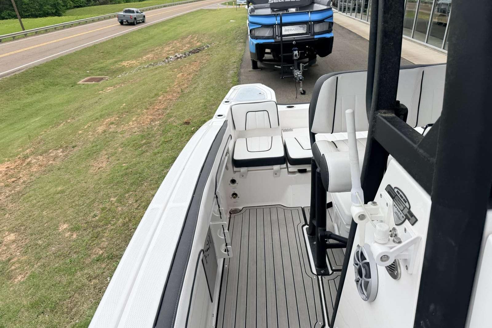 2023 Yamaha Boats 255 FSH Sport E interior with seating and controls, parked near a road.