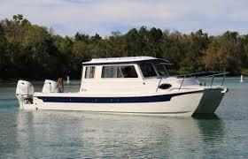 2026 C-Dory TOMCAT 255 boat on calm water with forested background.