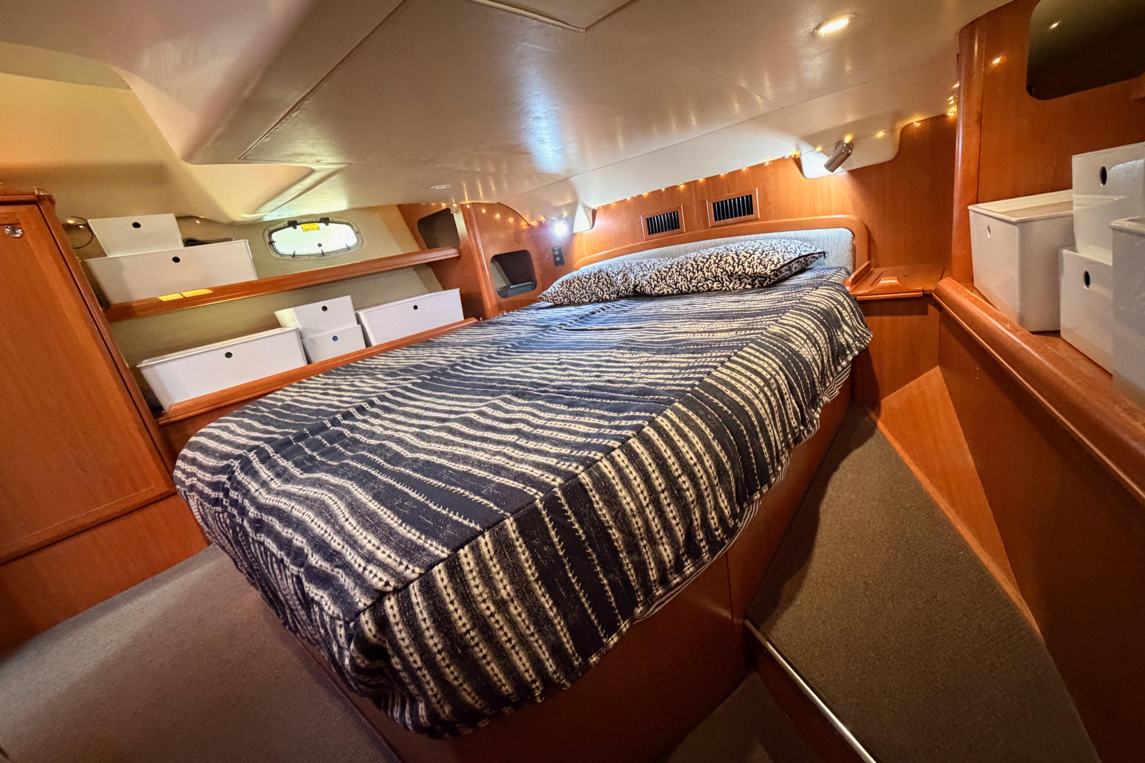 Cozy cabin interior of 2008 Hunter 45 Deck Salon with striped bedding and storage.