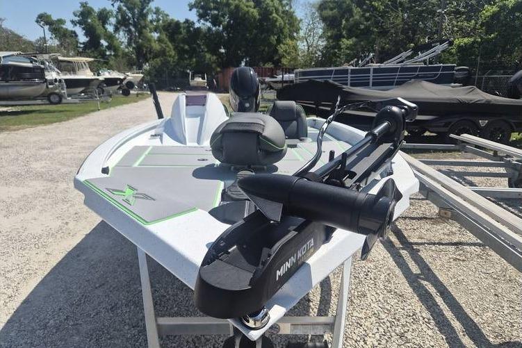 2026 Xpress H18 boat with Minn Kota motor, parked outdoors on gravel.