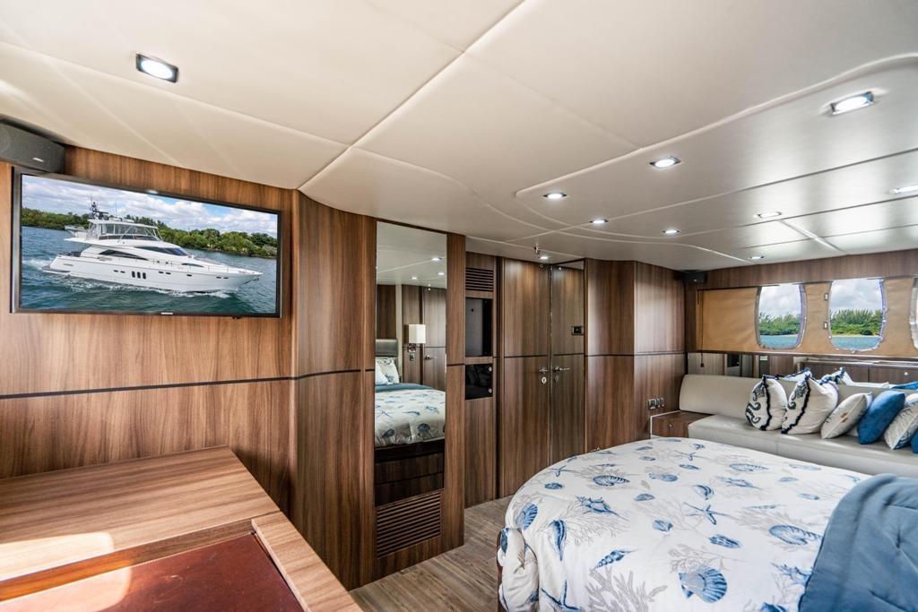 Luxurious interior of 2020 Fairline 68 yacht with elegant wood paneling and plush bedding.