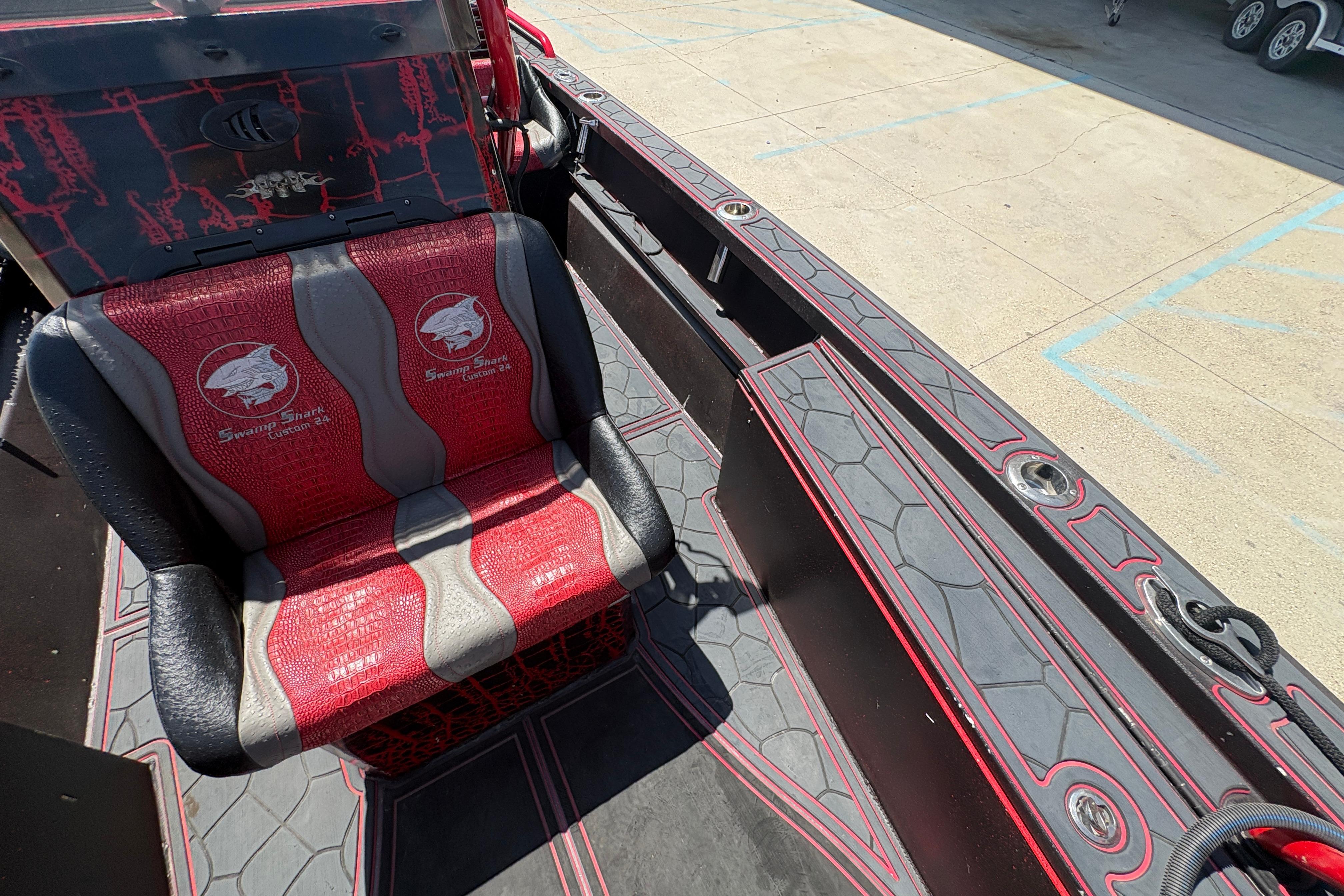 Red and black interior of a 2018 Custom Swamp Shark 24' boat, featuring branded seating.