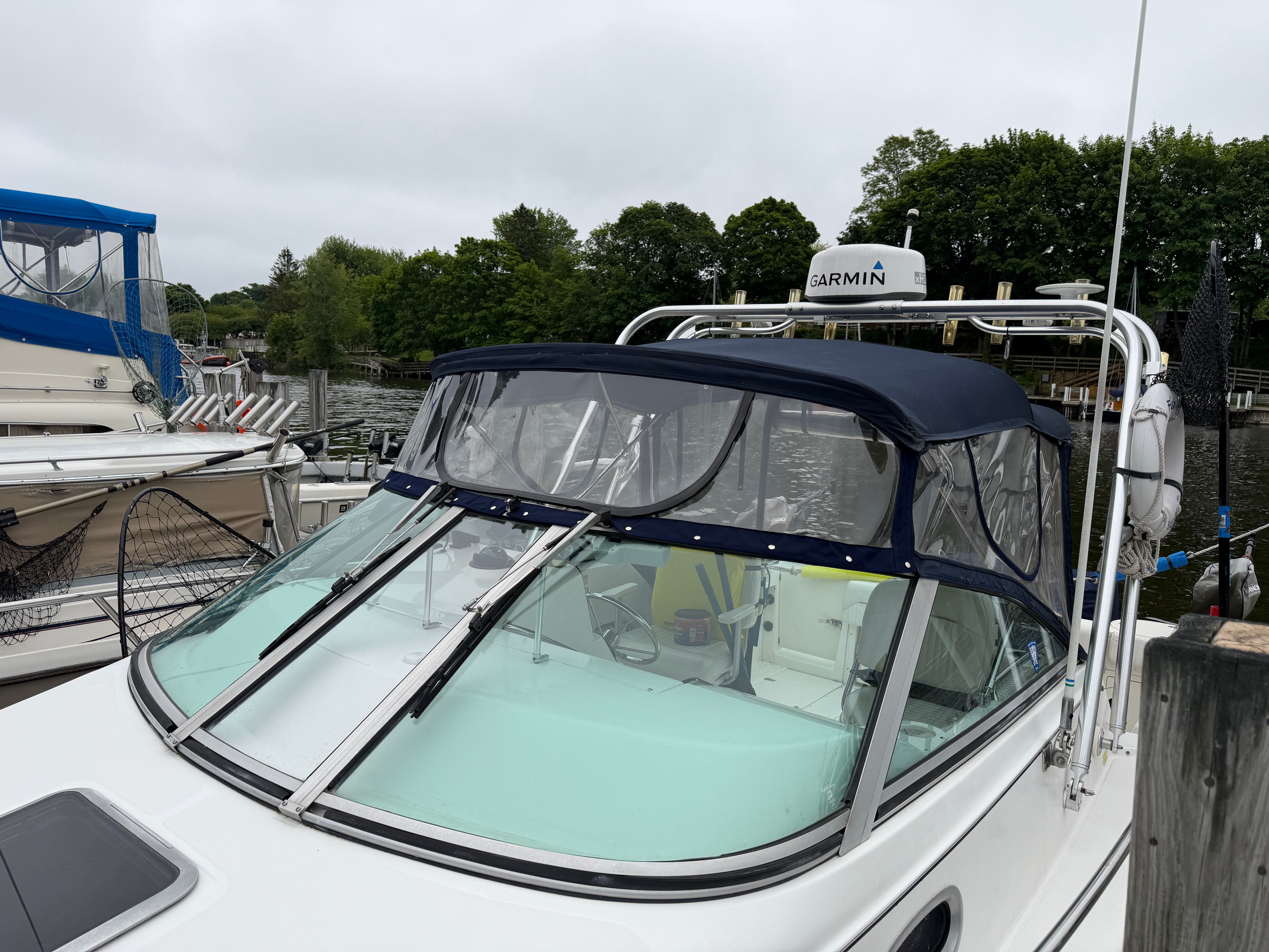 A 2001 Boston Whaler 26 Conquest docked, featuring a blue canopy.